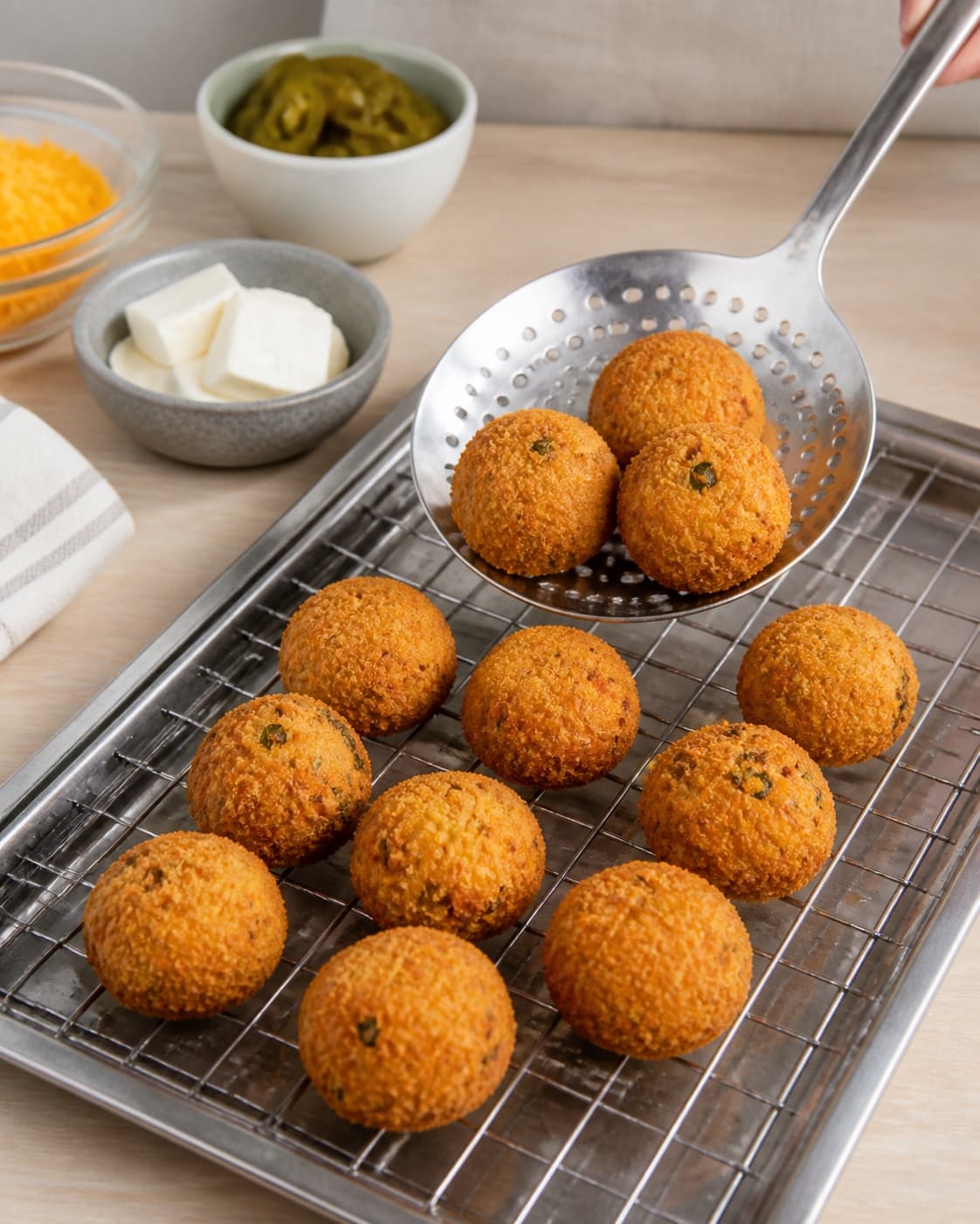 One single photorealistic instructional frame of the crisp fried pieces draining on one rack for Chili Cheese Tops, featuring cheddar, flødeost, jalapeños, with only the named equipment and no unrelated food, text, logos or packaging under tilberedningen af chili cheese tops