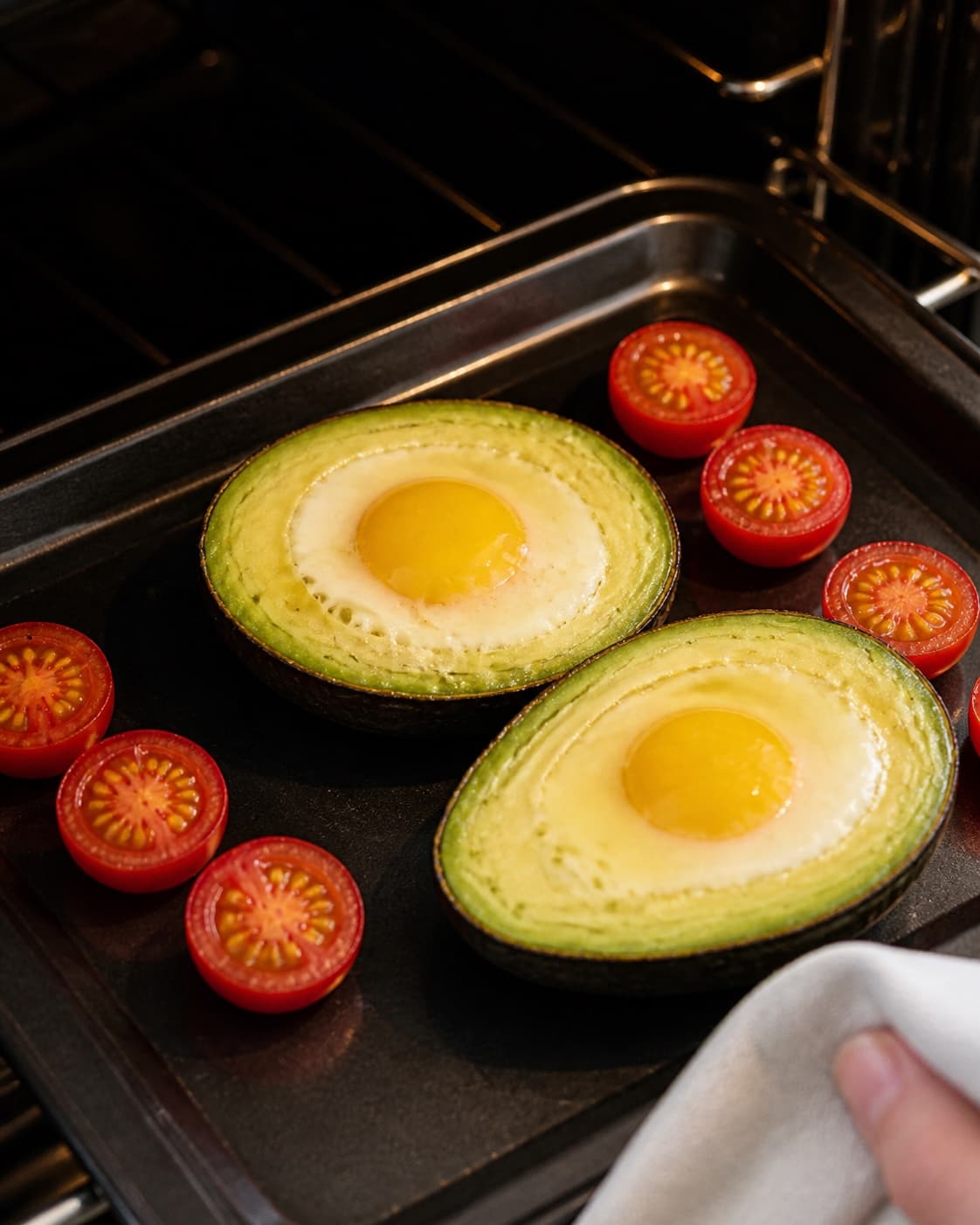 One single photorealistic instructional frame of the egg mixture gently setting around the filling for Bagt avocado med æg, featuring avocado, æg, cherrytomater, with only the named equipment and no unrelated food, text, logos or packaging under tilberedningen af bagt avocado med æg