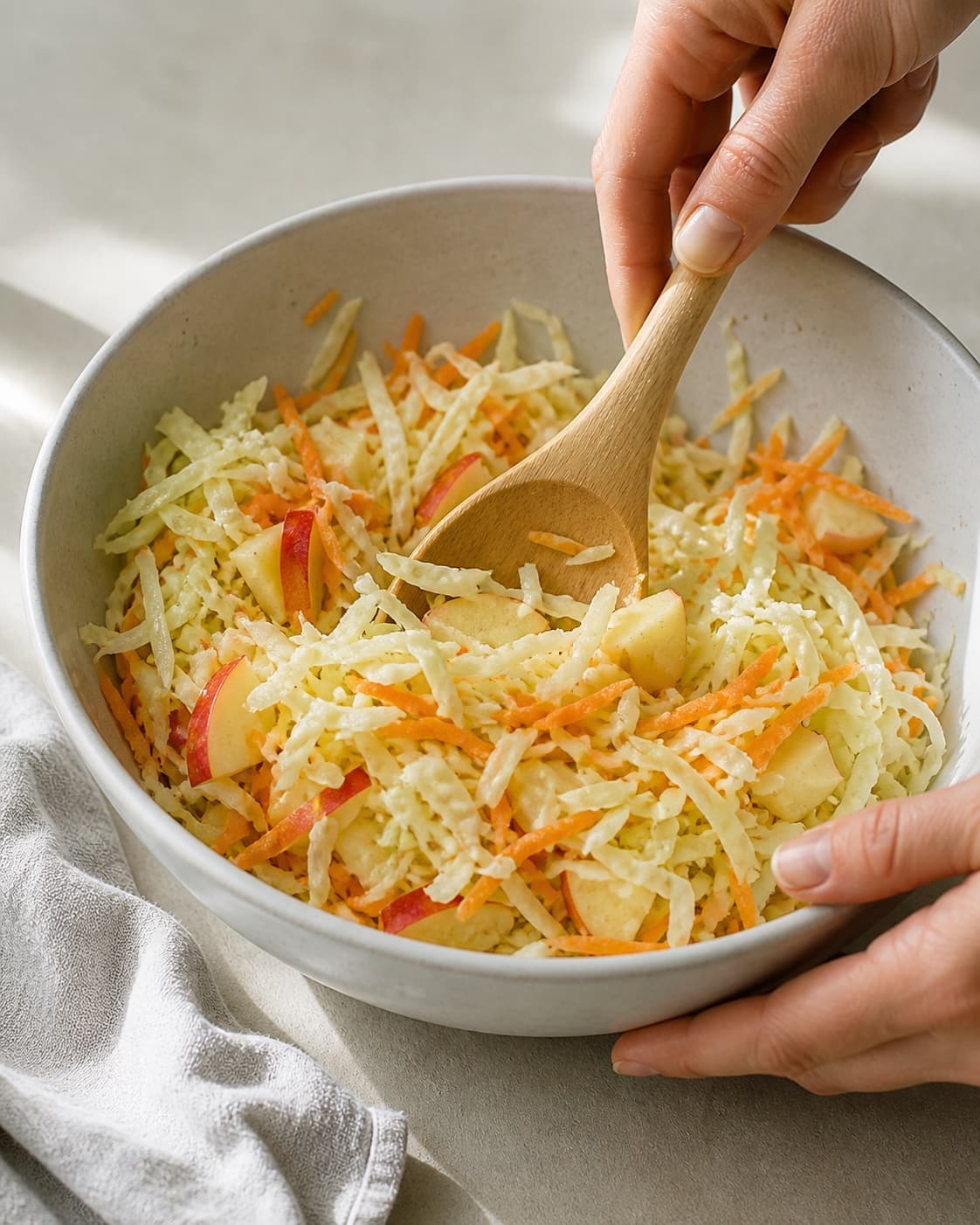 One single photorealistic instructional frame of the prepared salad components being gently tossed together for Hvidkålssalat, featuring hvidkål, gulerødder, æble, with only the named equipment and no unrelated food, text, logos or packaging under tilberedningen af hvidkålssalat