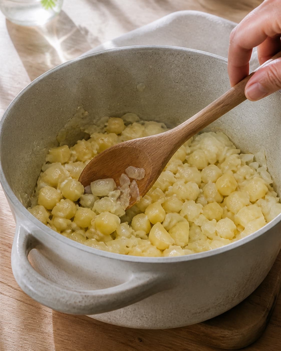 One single photorealistic instructional frame of aromatic vegetables softening in the same heavy pot for Skipperlabskovs, featuring oksebov, kartofler, løg, with only the named equipment and no unrelated food, text, logos or packaging under tilberedningen af skipperlabskovs