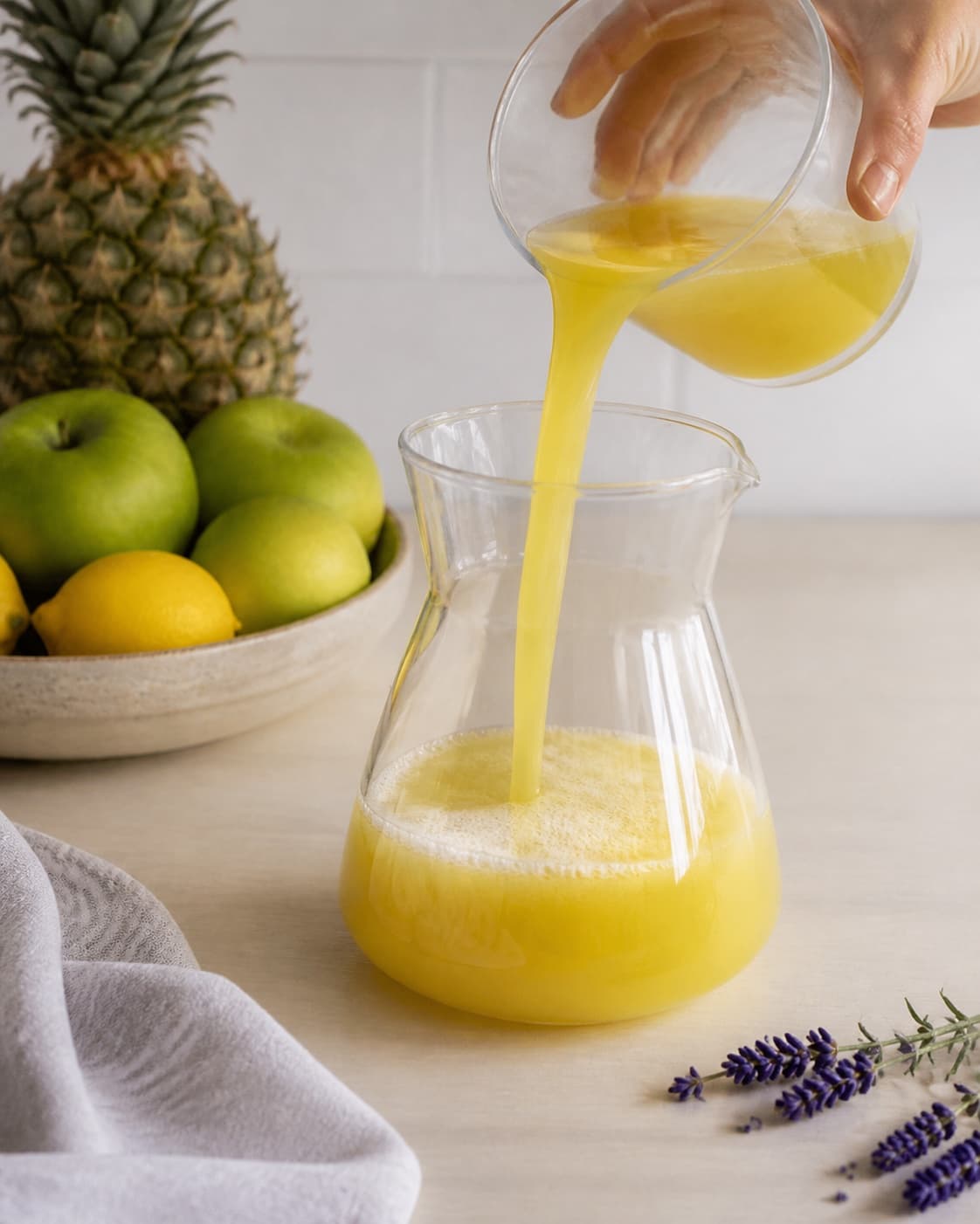 One single photorealistic instructional frame of colorful fresh juice flowing into one clean jug for Ananas Lavendel Juice, featuring ananas, æbler, citron, with only the named equipment and no unrelated food, text, logos or packaging under tilberedningen af ananas lavendel juice