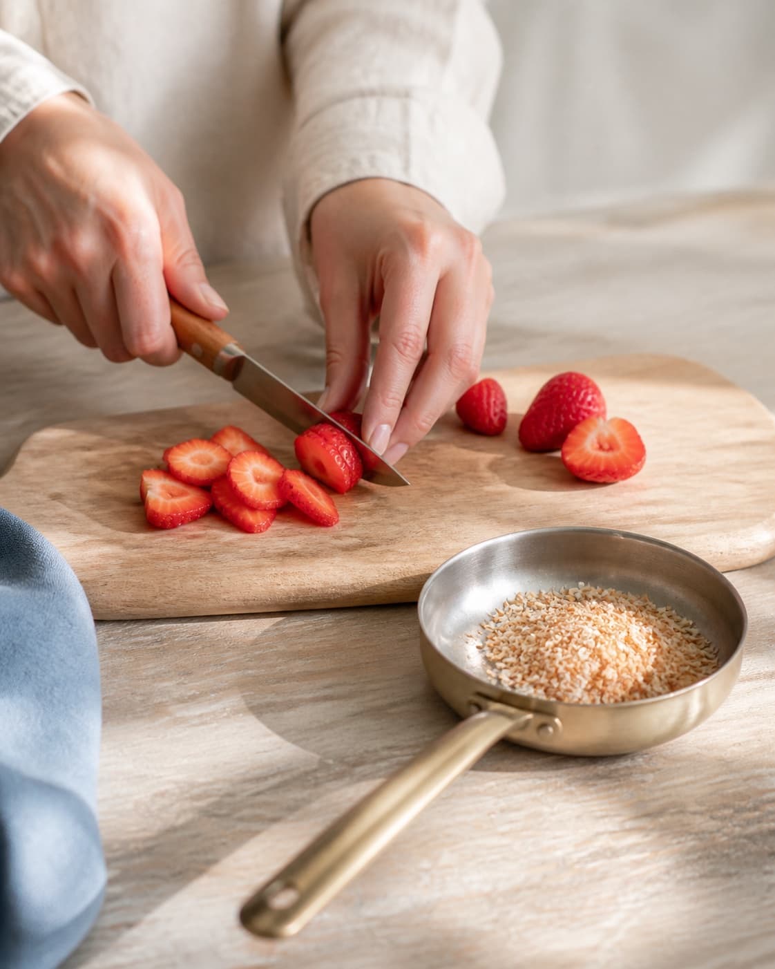 One single photorealistic instructional frame of fresh fruit being cut beside one small pan of toasted topping for Chiagrød, featuring chiafrø, mælk, vanilje, with only the named equipment and no unrelated food, text, logos or packaging under tilberedningen af chiagrød