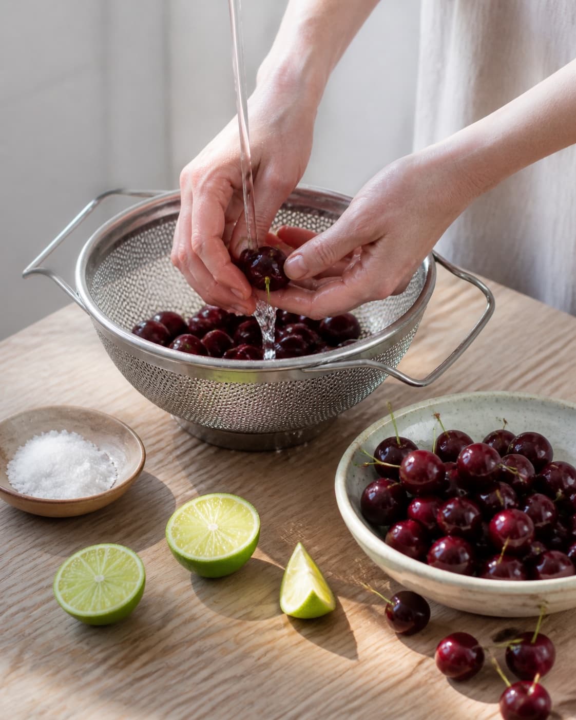 One single photorealistic instructional frame of fresh produce being washed and trimmed for Kirsebærsaft, featuring kirsebær, lime, sukker, with only the named equipment and no unrelated food, text, logos or packaging under tilberedningen af kirsebærsaft