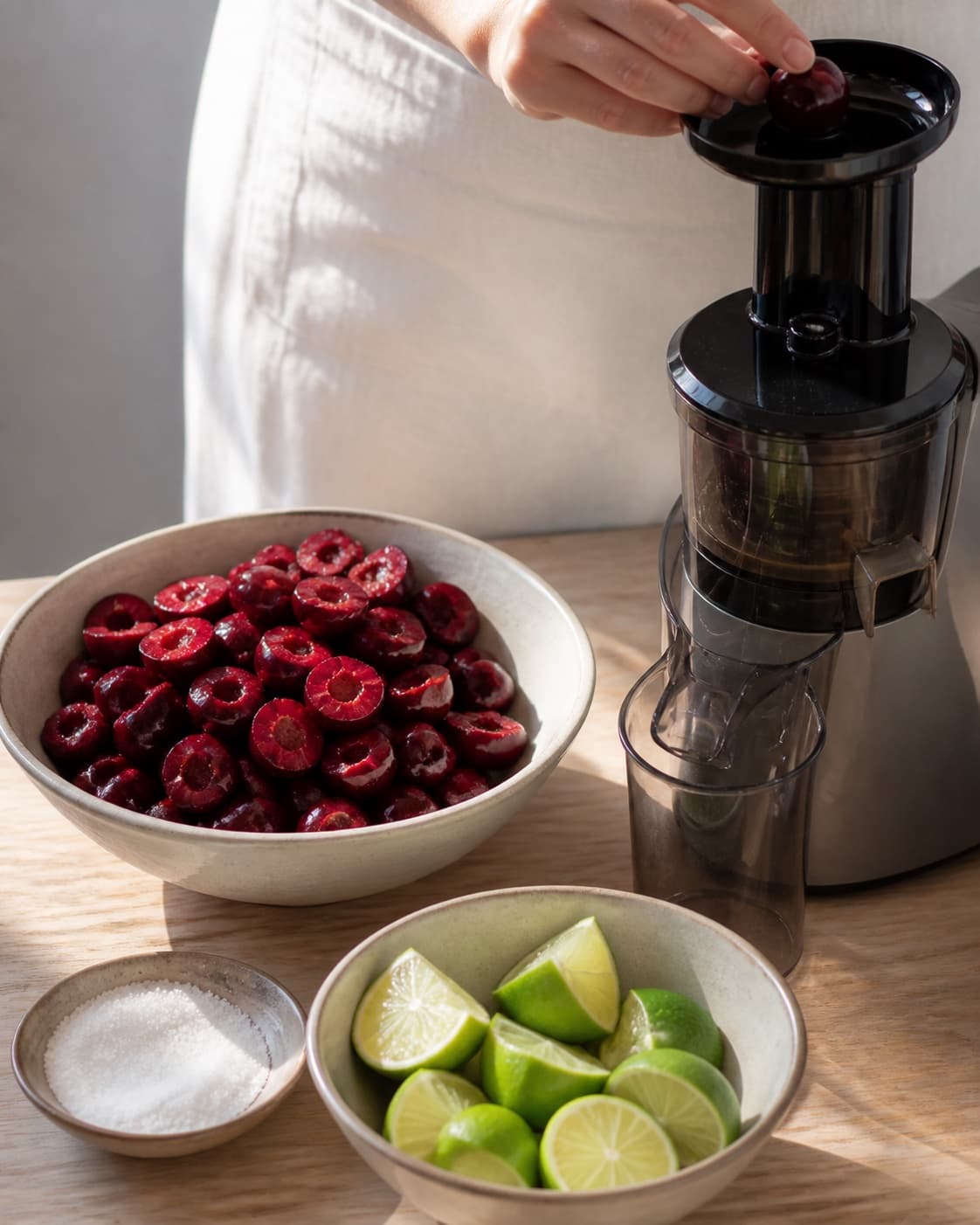 One single photorealistic instructional frame of the produce cut into juicer-size pieces for Kirsebærsaft, featuring kirsebær, lime, sukker, with only the named equipment and no unrelated food, text, logos or packaging under tilberedningen af kirsebærsaft