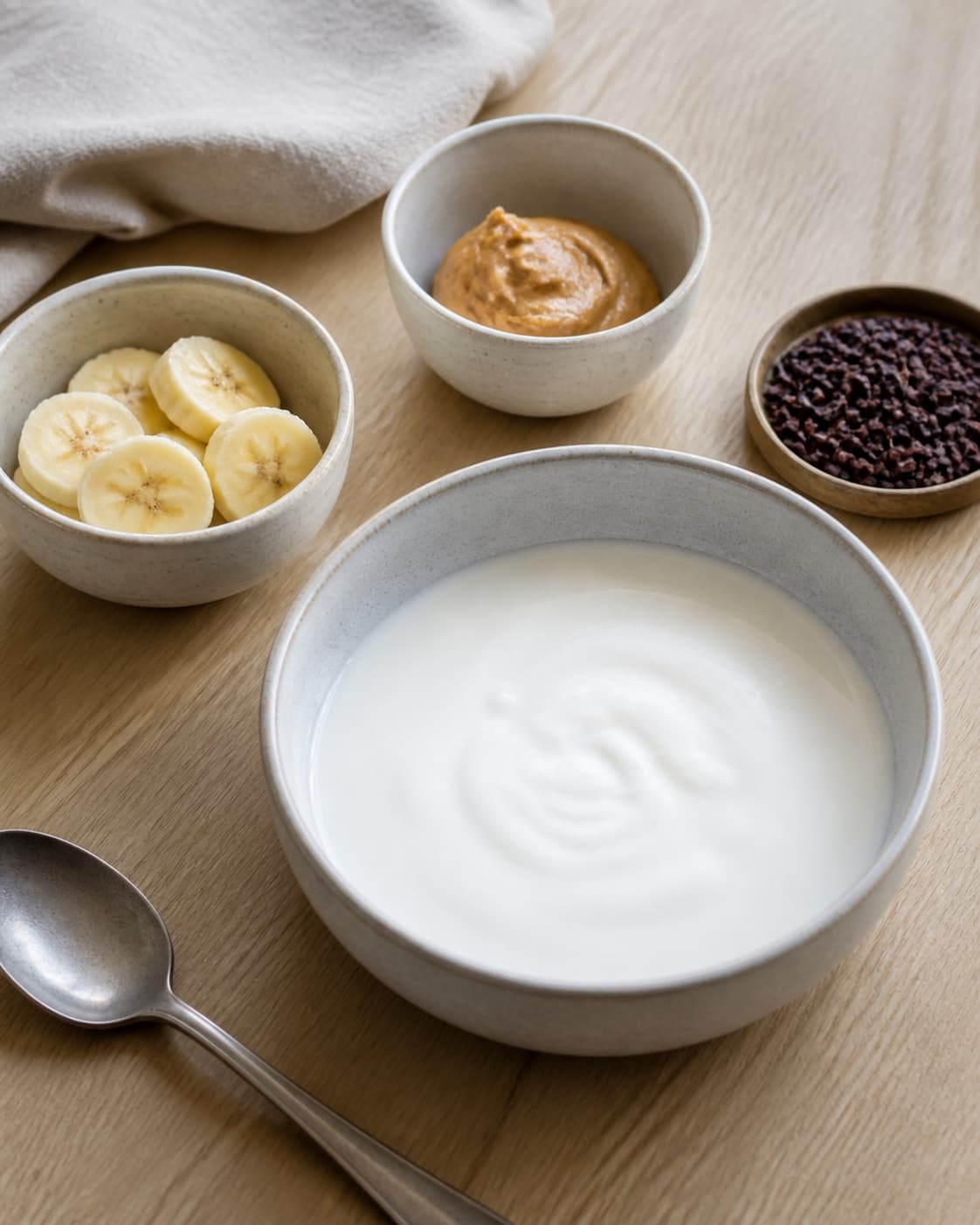 One single photorealistic instructional frame of measured grains seeds and liquid before cooking for Frugtyoghurt med banan, peanutbutter og kakaonibs, featuring yoghurt naturel, banan, peanutbutter, with only the named equipment and no unrelated food, text, logos or packaging under tilberedningen af frugtyoghurt med banan, peanutbutter og kakaonibs