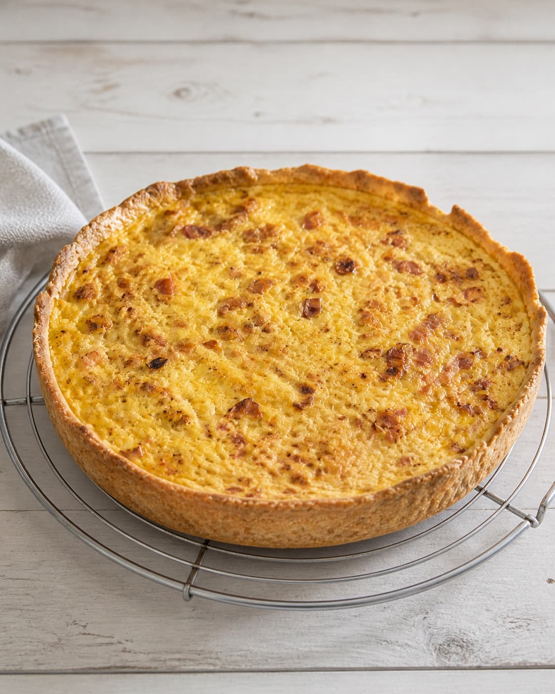 One single photorealistic instructional frame of the completed pastries cooling neatly on one rack for Quiche lorraine, featuring hvedemel, smør, bacon, with only the named equipment and no unrelated food, text, logos or packaging under tilberedningen af quiche lorraine