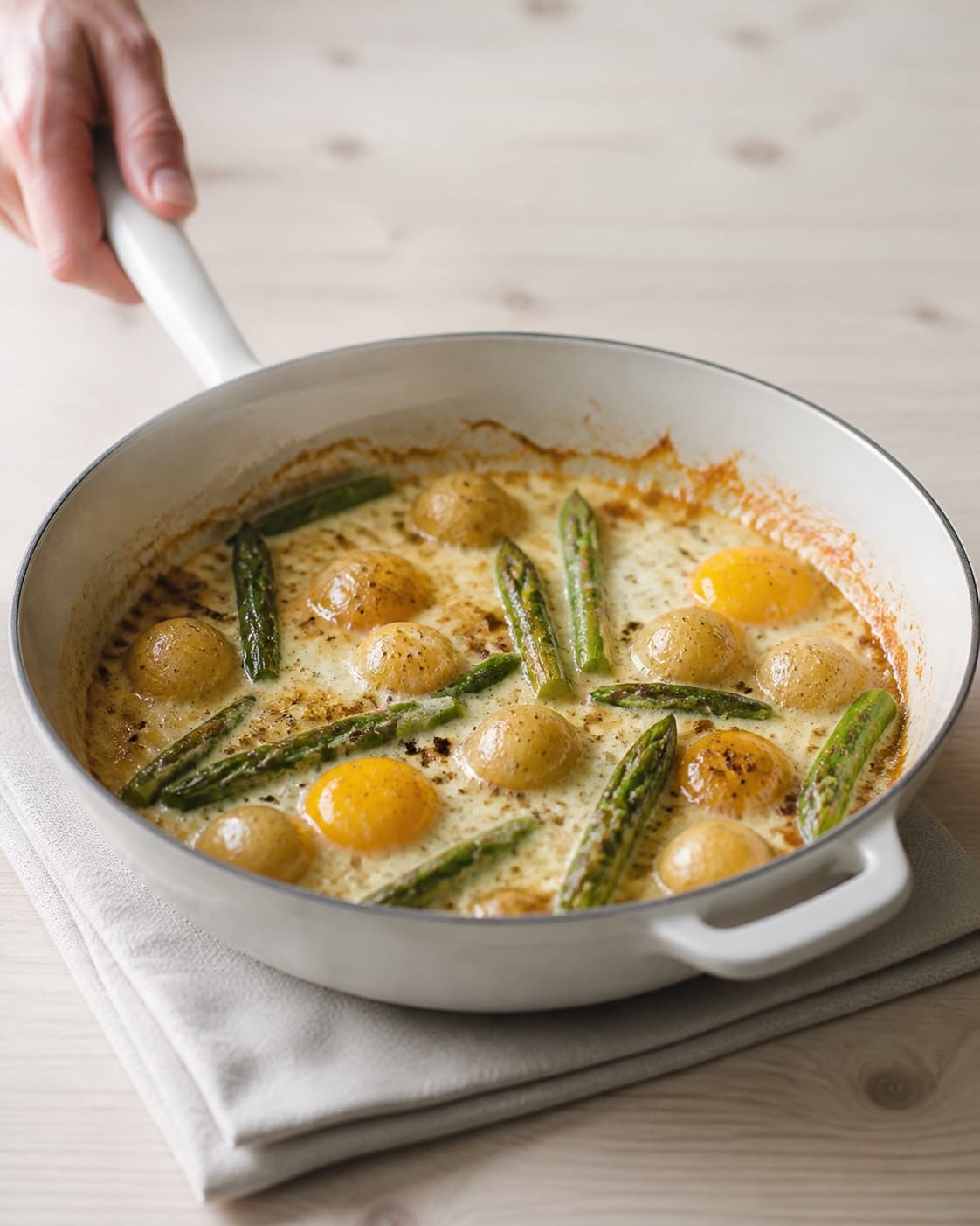 One single photorealistic instructional frame of the savoury filling browning in one skillet for Asparges og kartofler en cocotte, featuring grønne asparges, små kartofler, æg, with only the named equipment and no unrelated food, text, logos or packaging under tilberedningen af asparges og kartofler en cocotte