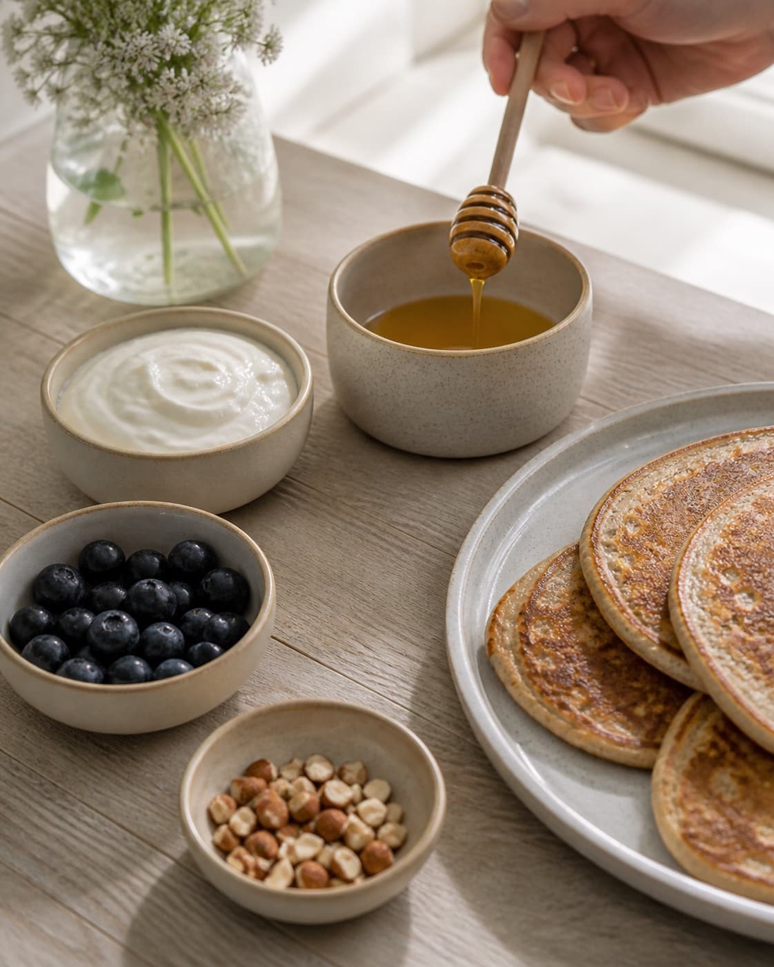 Honey and a restrained fresh topping prepared in small bowls for buckwheat pancakes, no strawberries unless explicitly shown, no saucepan under tilberedningen af boghvedepandekager