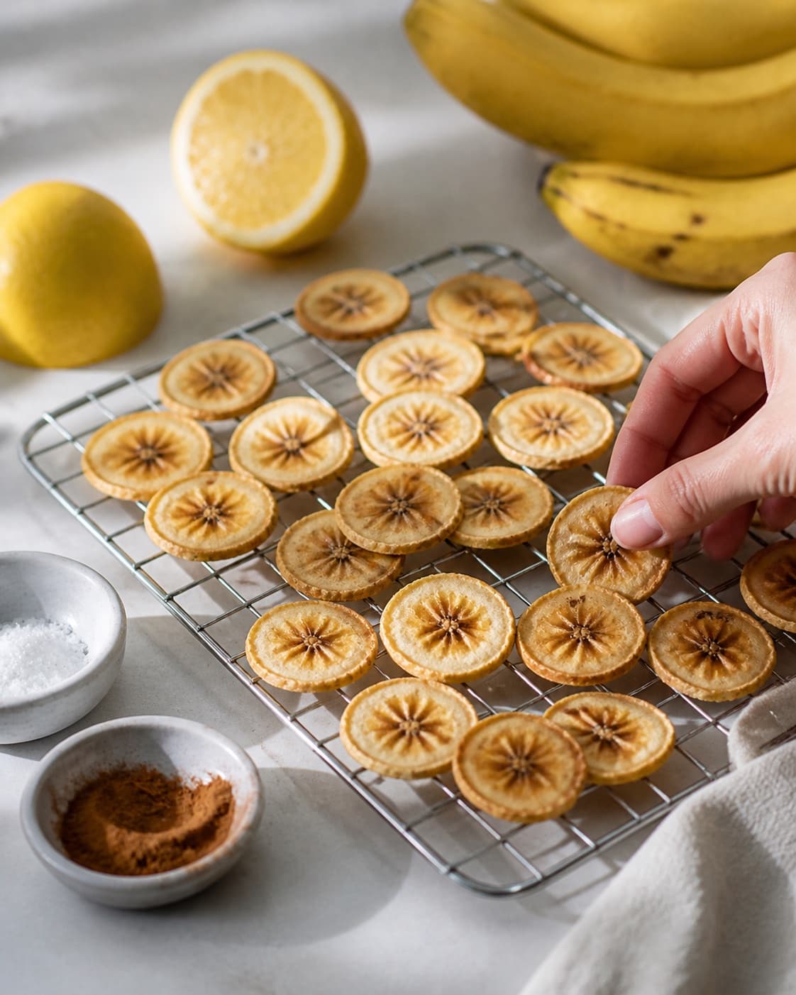 One single photorealistic instructional frame of the cooked ingredient resting uncovered on one rack or platter for Bananchips, featuring bananer, citron, stødt kanel, with only the named equipment and no unrelated food, text, logos or packaging under tilberedningen af bananchips