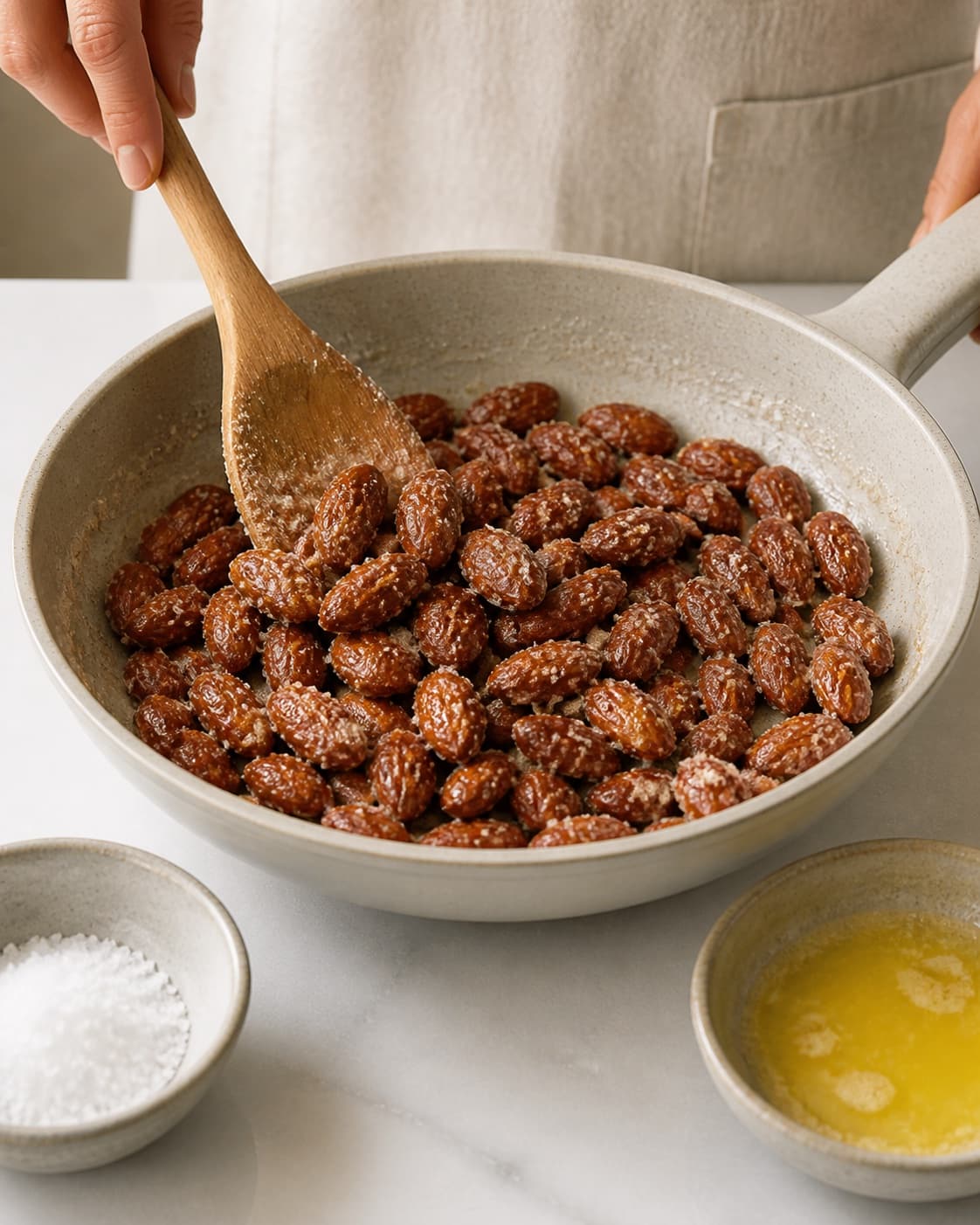 One single photorealistic instructional frame of the main ingredient being evenly coated with seasoning for Søde saltede mandler, featuring mandler, sukker, smør, with only the named equipment and no unrelated food, text, logos or packaging under tilberedningen af søde saltede mandler
