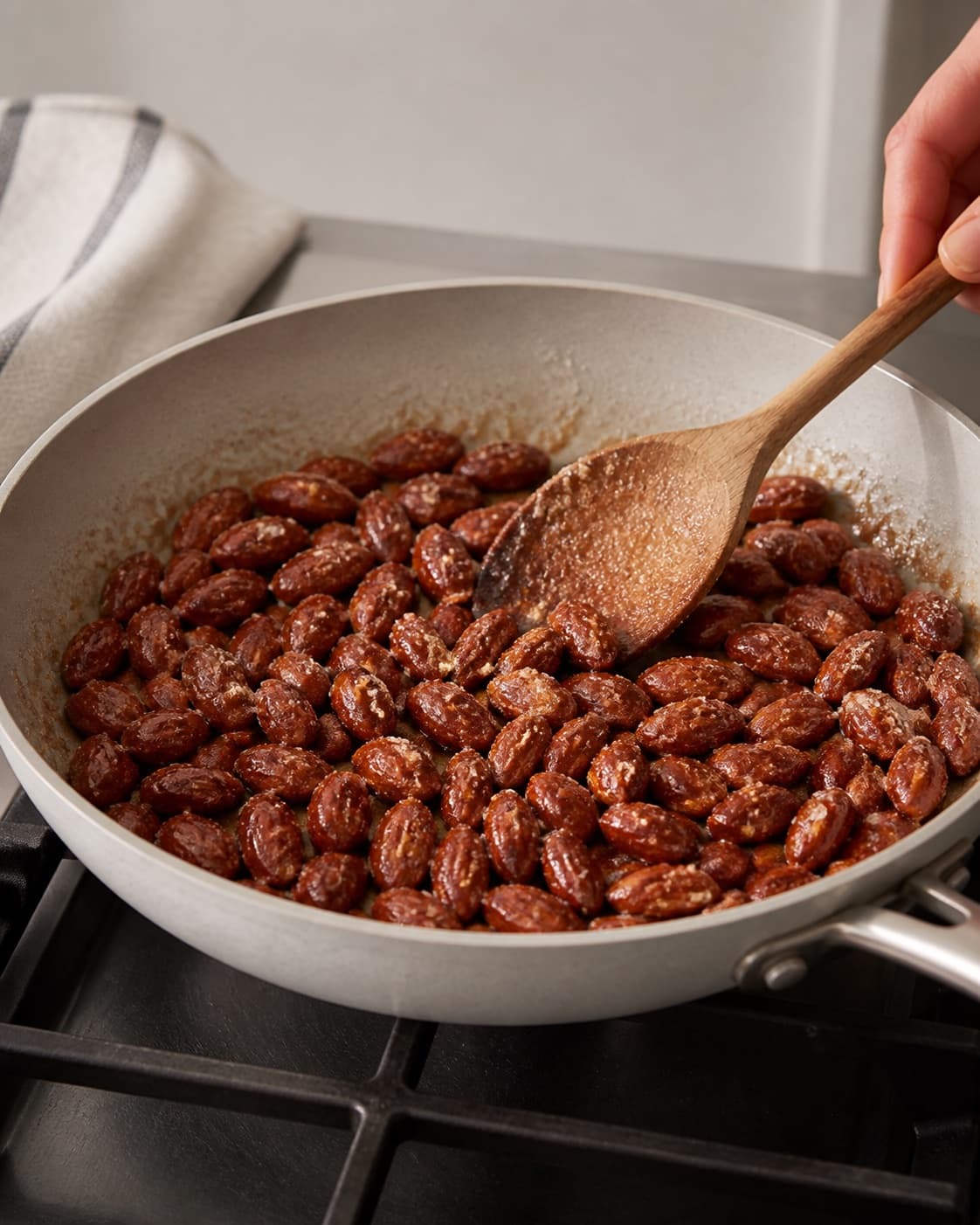 One single photorealistic instructional frame of the seasoned main ingredient roasting until properly cooked for Søde saltede mandler, featuring mandler, sukker, smør, with only the named equipment and no unrelated food, text, logos or packaging under tilberedningen af søde saltede mandler