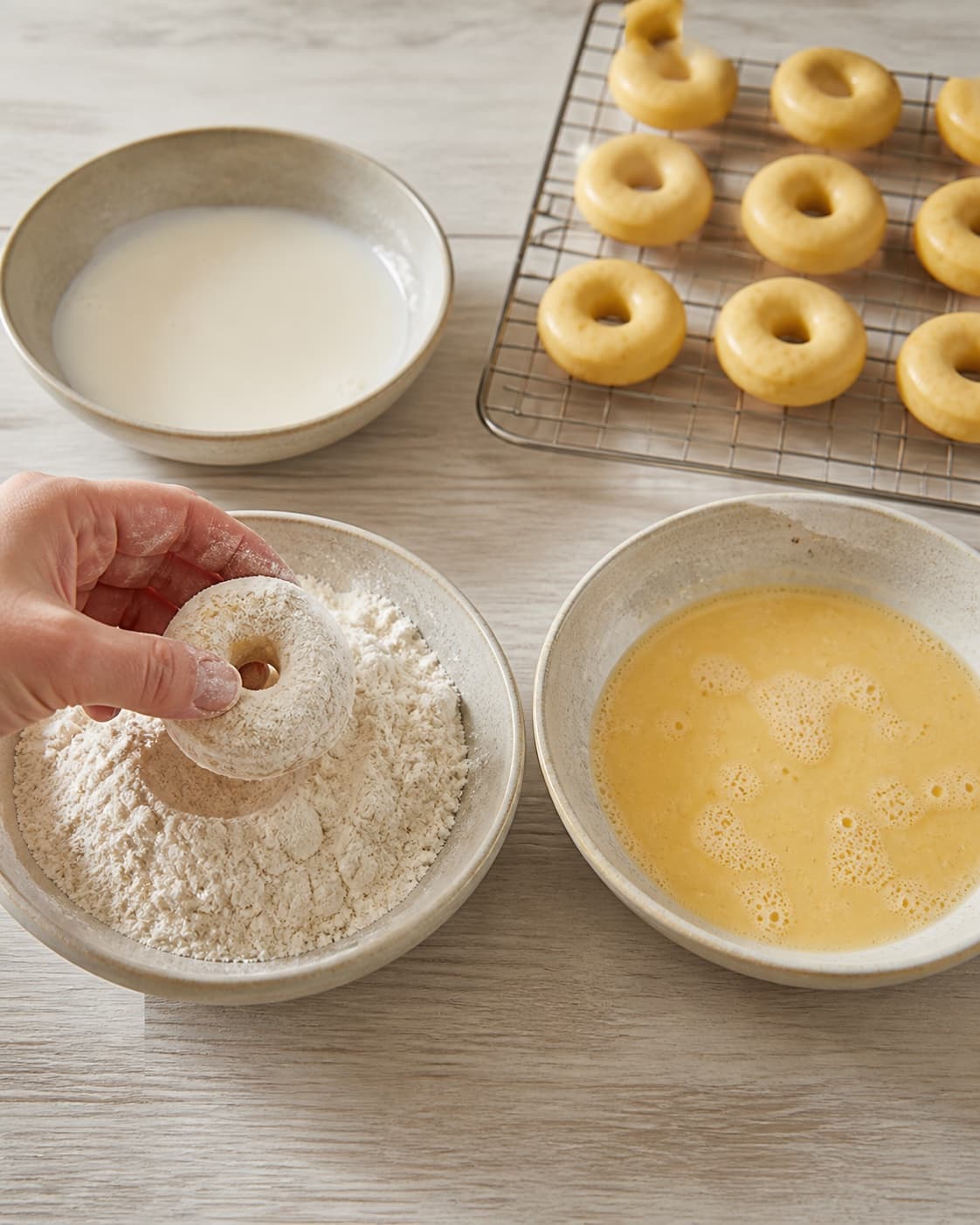 One single photorealistic instructional frame of uniform raw pieces prepared for breading for Mini donuts med safran, featuring hvedemel, æg, mælk, with only the named equipment and no unrelated food, text, logos or packaging under tilberedningen af mini donuts med safran