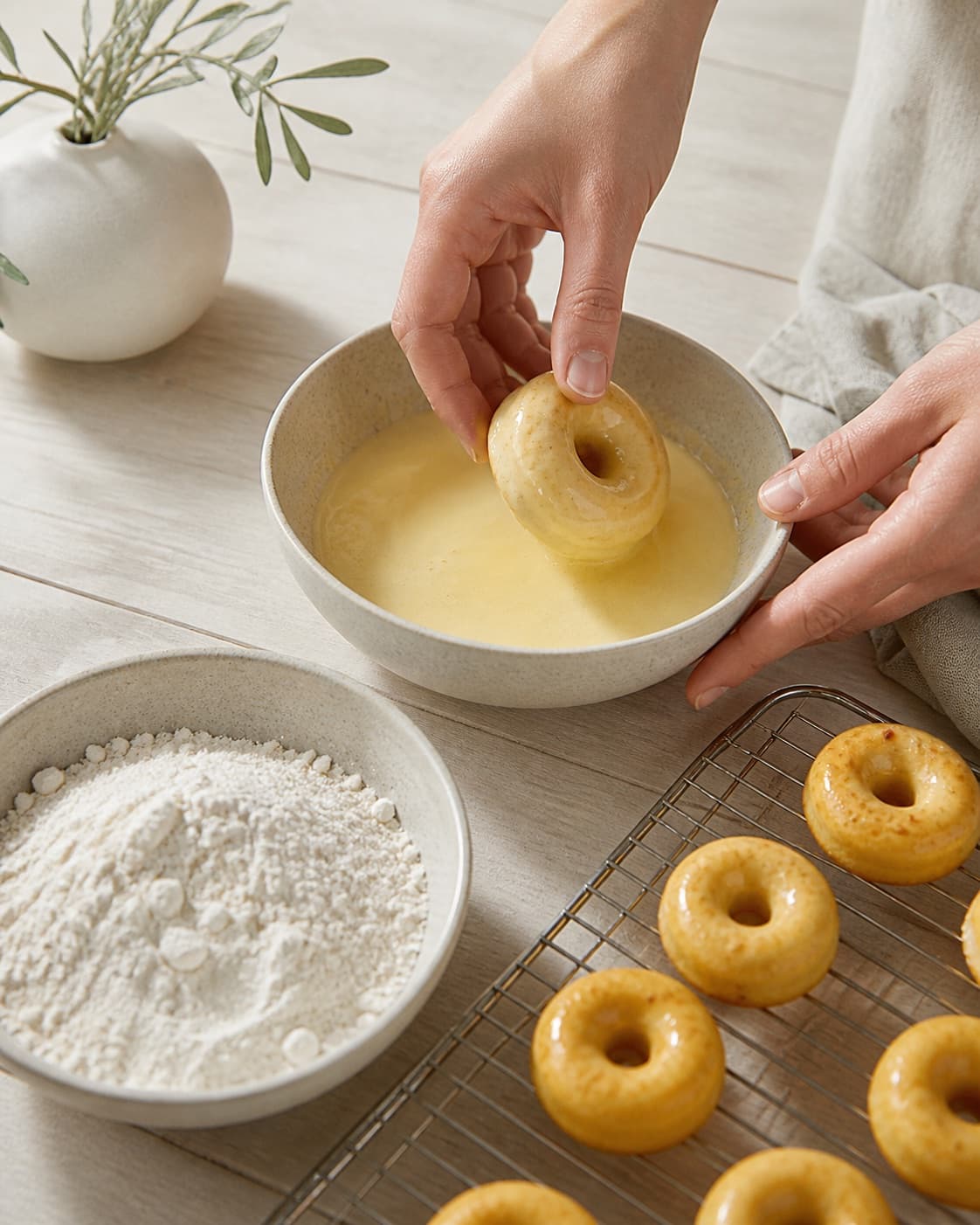 One single photorealistic instructional frame of realistic hands evenly coating each piece for Mini donuts med safran, featuring hvedemel, æg, mælk, with only the named equipment and no unrelated food, text, logos or packaging under tilberedningen af mini donuts med safran