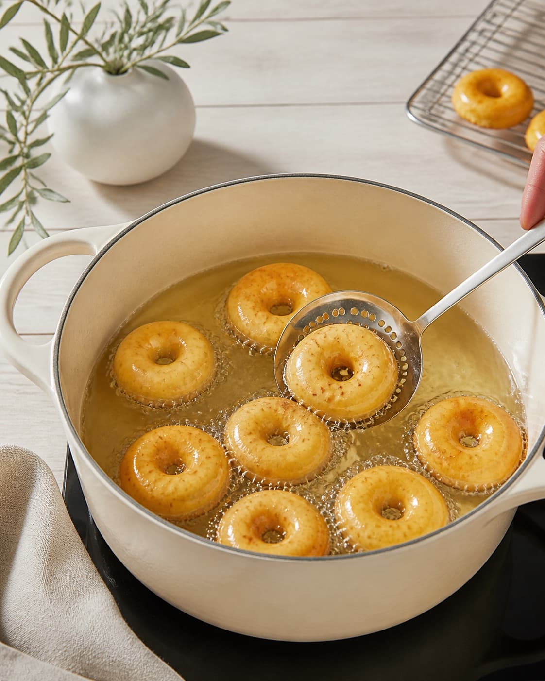 One single photorealistic instructional frame of golden pieces frying in clear oil in one pot for Mini donuts med safran, featuring hvedemel, æg, mælk, with only the named equipment and no unrelated food, text, logos or packaging under tilberedningen af mini donuts med safran