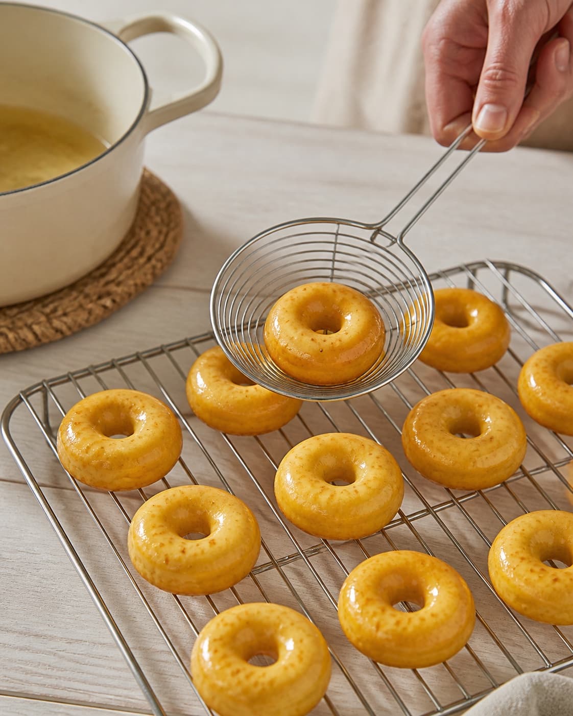 One single photorealistic instructional frame of the crisp fried pieces draining on one rack for Mini donuts med safran, featuring hvedemel, æg, mælk, with only the named equipment and no unrelated food, text, logos or packaging under tilberedningen af mini donuts med safran