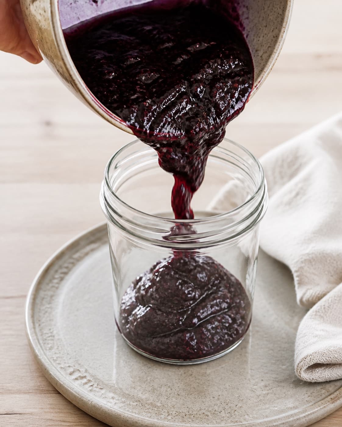 Hot thick brombærsyltetøj being poured into one sterilized jar, no raw fruit layers or clear brine under tilberedningen af brombærsyltetøj