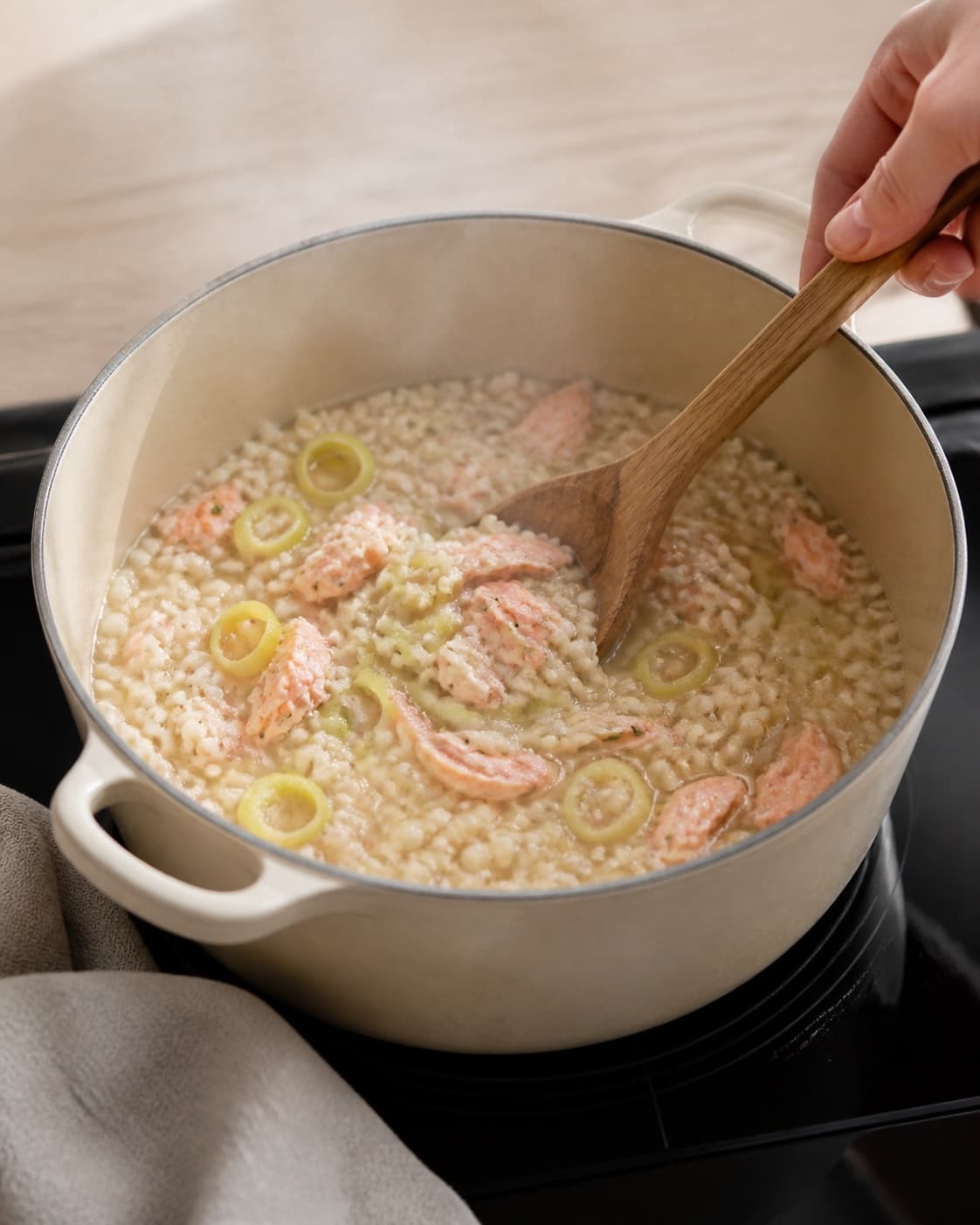 One single photorealistic instructional frame of the stew gently braising with tender meat and vegetables for Bygotto med varmrøget laks, featuring perlebyg, varmrøget laks, porrer, with only the named equipment and no unrelated food, text, logos or packaging under tilberedningen af bygotto med varmrøget laks