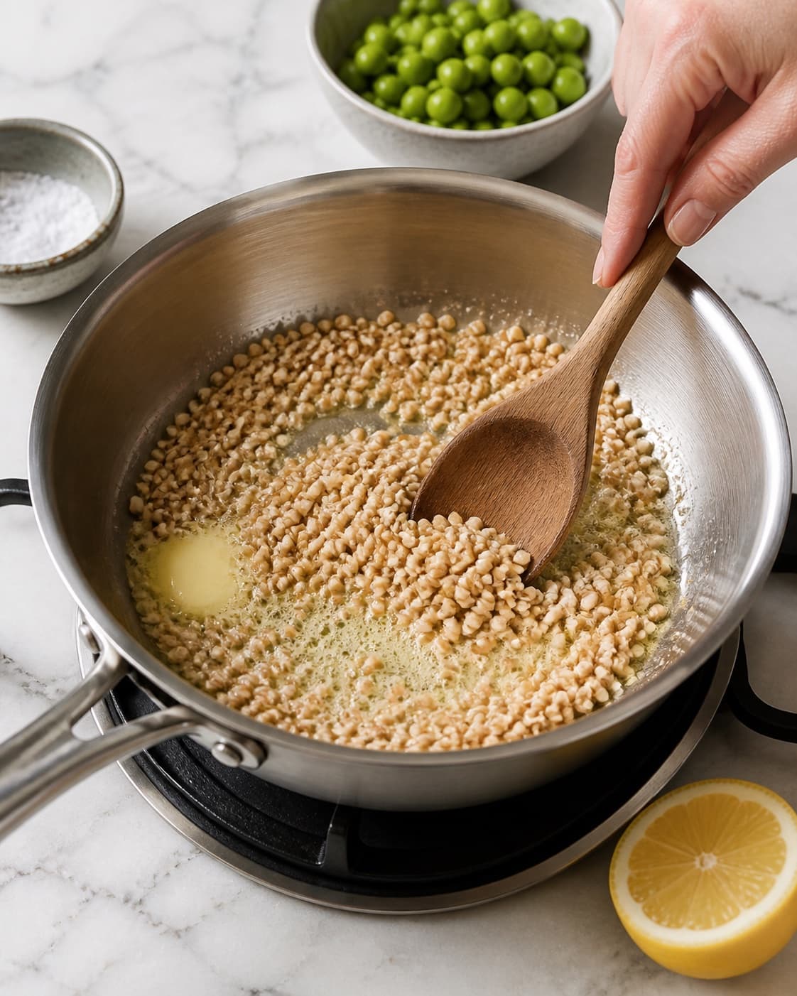 Spelt grains being toasted gently in butter in one saucepan, no meat cubes or browned beef under tilberedningen af speltotto med ærter og citron