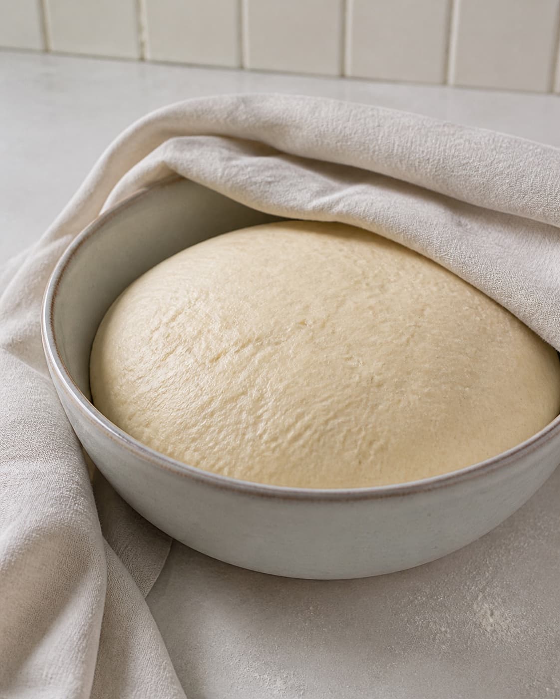 One single photorealistic instructional frame of risen pizza dough in one covered bowl for Mini pizza med asparges, featuring hvedemel, gær, grønne asparges, with only the named equipment and no unrelated food, text, logos or packaging under tilberedningen af mini pizza med asparges