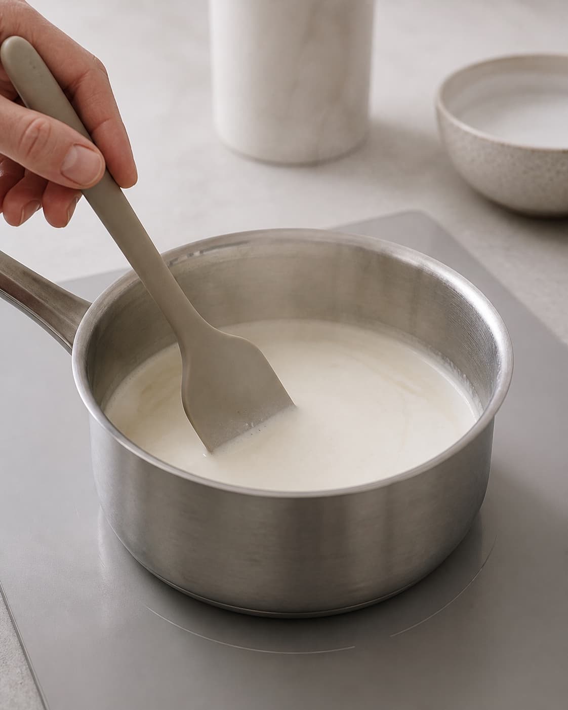One single photorealistic instructional frame of cream and milk warming gently in one saucepan for Bounty is, featuring kokosmælk, piskefløde, mørk chokolade, with only the named equipment and no unrelated food, text, logos or packaging under tilberedningen af bounty is