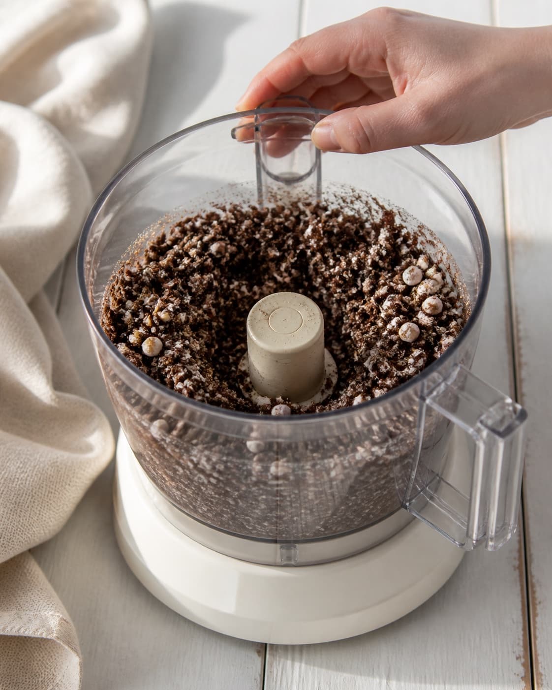 One single photorealistic instructional frame of the confection base becoming cohesive in one food processor for Chokoladepinde, featuring mørk chokolade, skumfiduser, hvid chokolade, with only the named equipment and no unrelated food, text, logos or packaging under tilberedningen af chokoladepinde
