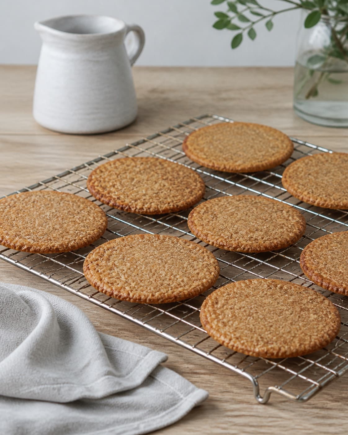 One single photorealistic instructional frame of the completed pastries cooling neatly on one rack for Rugkiks, featuring rugmel, hvedemel, smør, with only the named equipment and no unrelated food, text, logos or packaging under tilberedningen af rugkiks