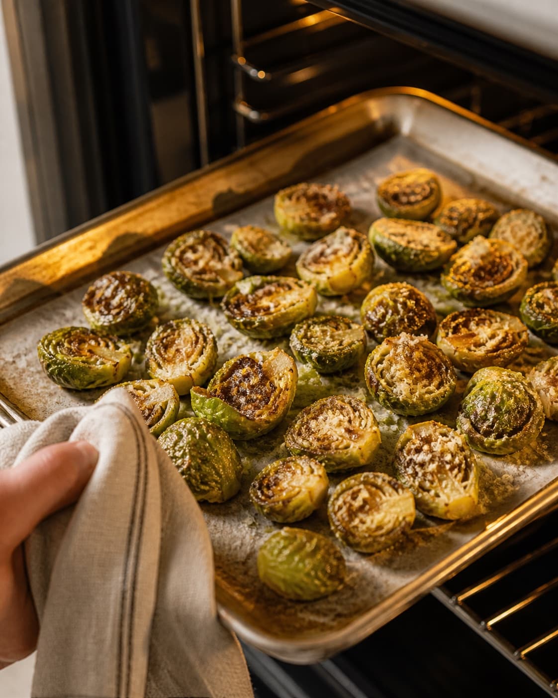 One single photorealistic instructional frame of the seasoned main ingredient roasting until properly cooked for Rosenkålschips, featuring rosenkål, olivenolie, parmesan, with only the named equipment and no unrelated food, text, logos or packaging under tilberedningen af rosenkålschips