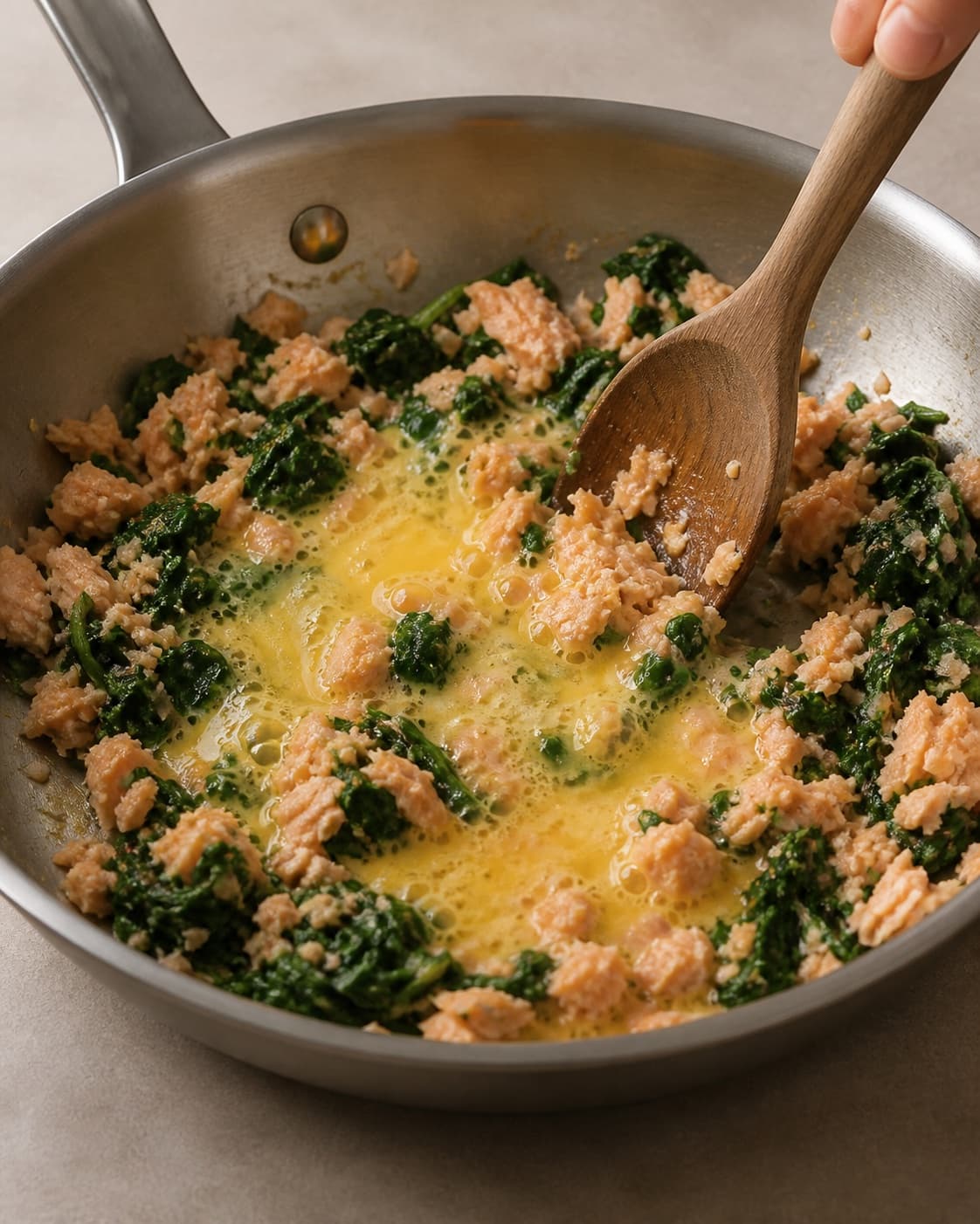 One single photorealistic instructional frame of the recipe-specific filling cooked in one pan for Ravioli af fuldkornsdurum med laks og spinat, featuring fuldkornsdurummel, æg, laks, with only the named equipment and no unrelated food, text, logos or packaging under tilberedningen af ravioli af fuldkornsdurum med laks og spinat