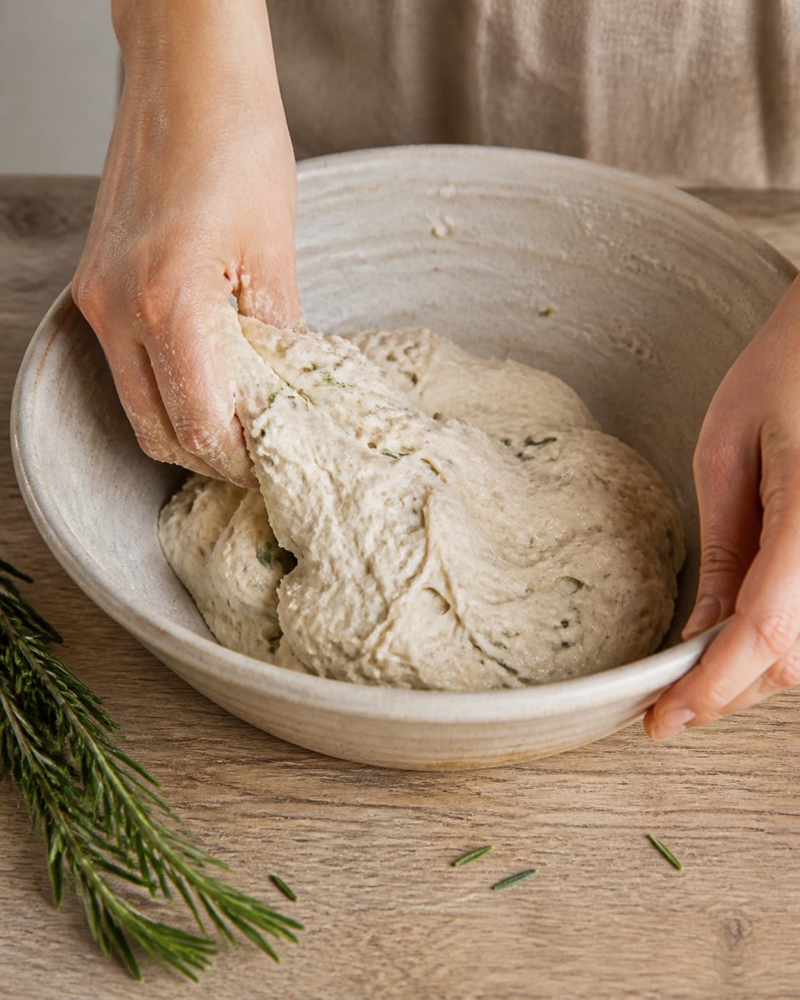One single photorealistic instructional frame of soft bread dough mixing in one bowl for Brød med rosmarin, featuring hvedemel, gær, frisk rosmarin, with only the named equipment and no unrelated food, text, logos or packaging under tilberedningen af brød med rosmarin