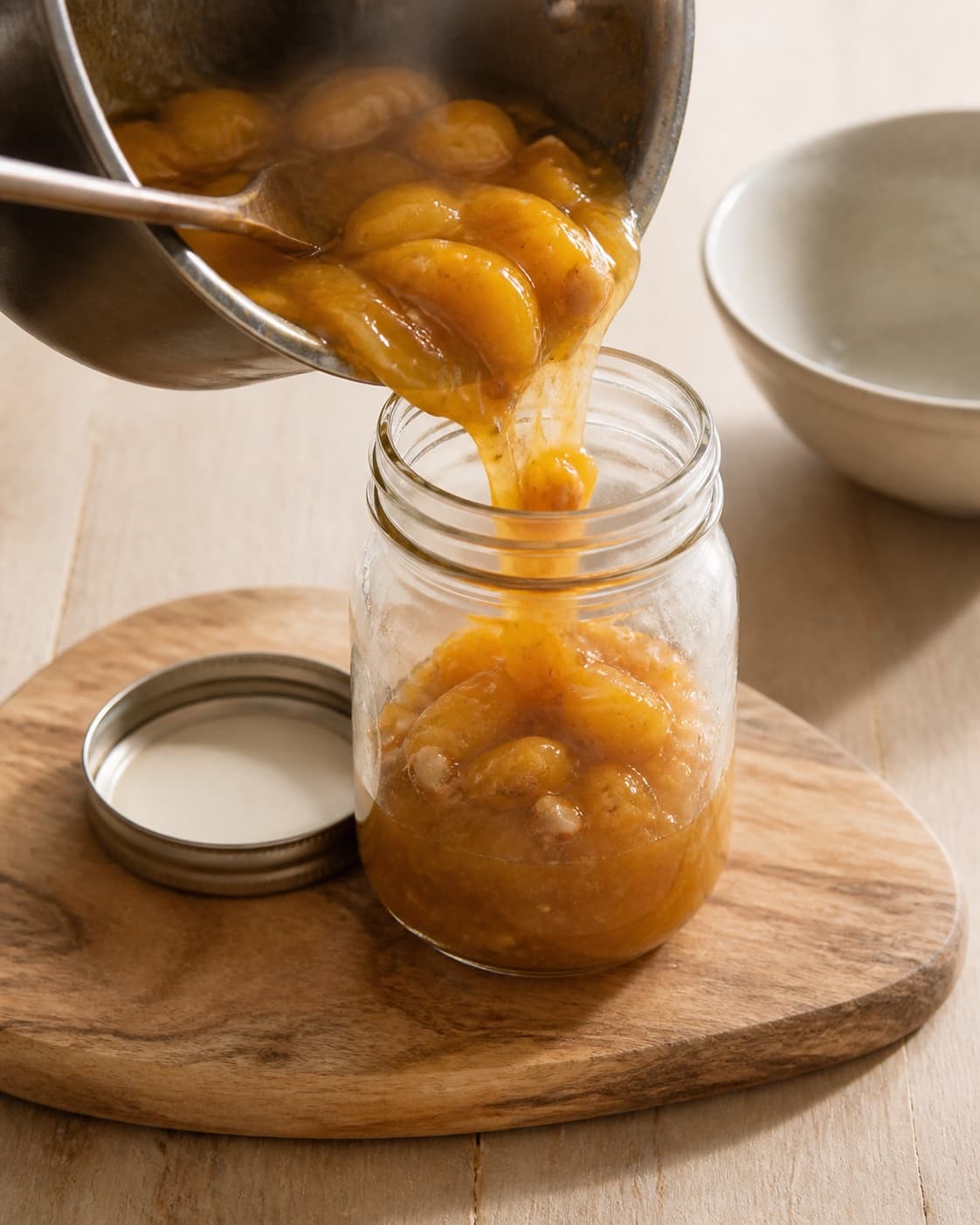 Hot thick ferskenkompot being poured into one sterilized jar, no raw fruit layers or clear brine under tilberedningen af ferskenkompot