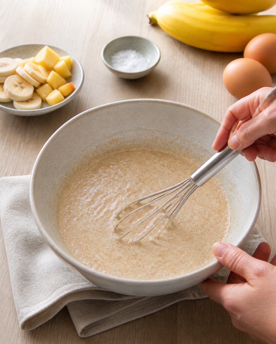 Smooth pourable batter for flourless banana and apple breakfast pancakes being whisked in one bowl, no saucepan, boiling porridge or finished pancakes under tilberedningen af morgenmadspandekager uden havregryn eller mel