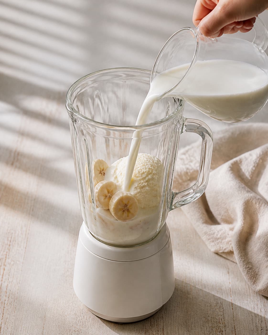 One single photorealistic instructional frame of prepared fruit and measured liquid beside one blender for Bananmilkshake med vaniljeis, featuring banan, vaniljeis, mælk, with only the named equipment and no unrelated food, text, logos or packaging under tilberedningen af bananmilkshake med vaniljeis