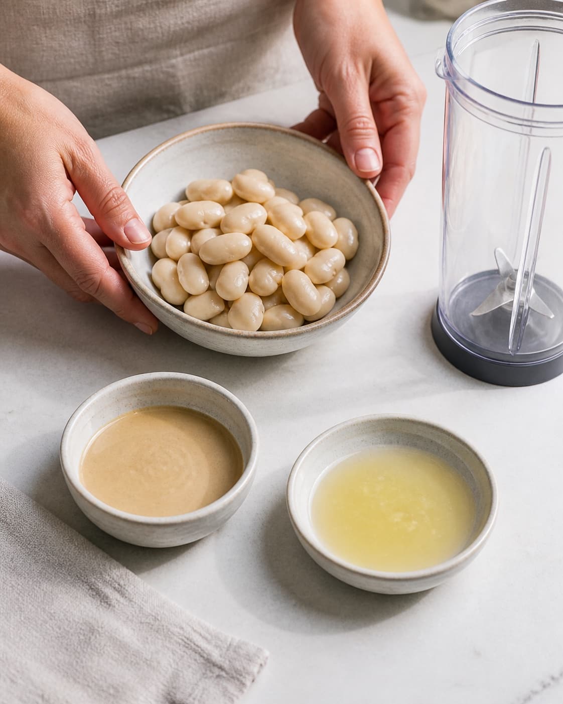 One single photorealistic instructional frame of the dip ingredients measured in separate small bowls for Butterbeans hummus, featuring butterbeans, tahin, citron, with only the named equipment and no unrelated food, text, logos or packaging under tilberedningen af butterbeans hummus
