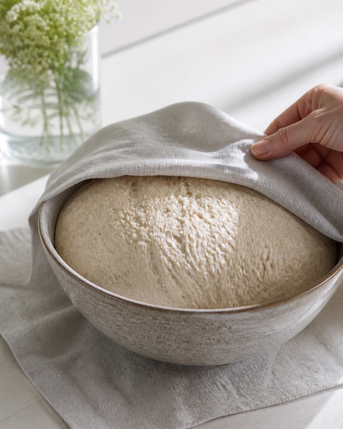 One single photorealistic instructional frame of elastic risen dough in one covered bowl for Verdens bedste hjemmebagte boller - og nemmeste, featuring hvedemel, gær, vand, with only the named equipment and no unrelated food, text, logos or packaging under tilberedningen af verdens bedste hjemmebagte boller - og nemmeste