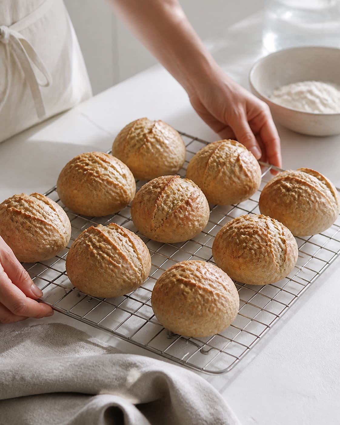 One single photorealistic instructional frame of freshly baked golden bread cooling on one rack for Verdens bedste hjemmebagte boller - og nemmeste, featuring hvedemel, gær, vand, with only the named equipment and no unrelated food, text, logos or packaging under tilberedningen af verdens bedste hjemmebagte boller - og nemmeste