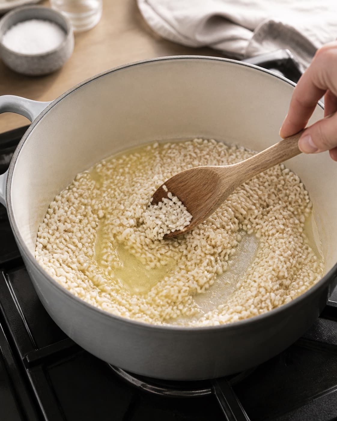 Risotto rice being toasted gently in butter in one saucepan, no meat cubes or browned beef under tilberedningen af safranrisotto