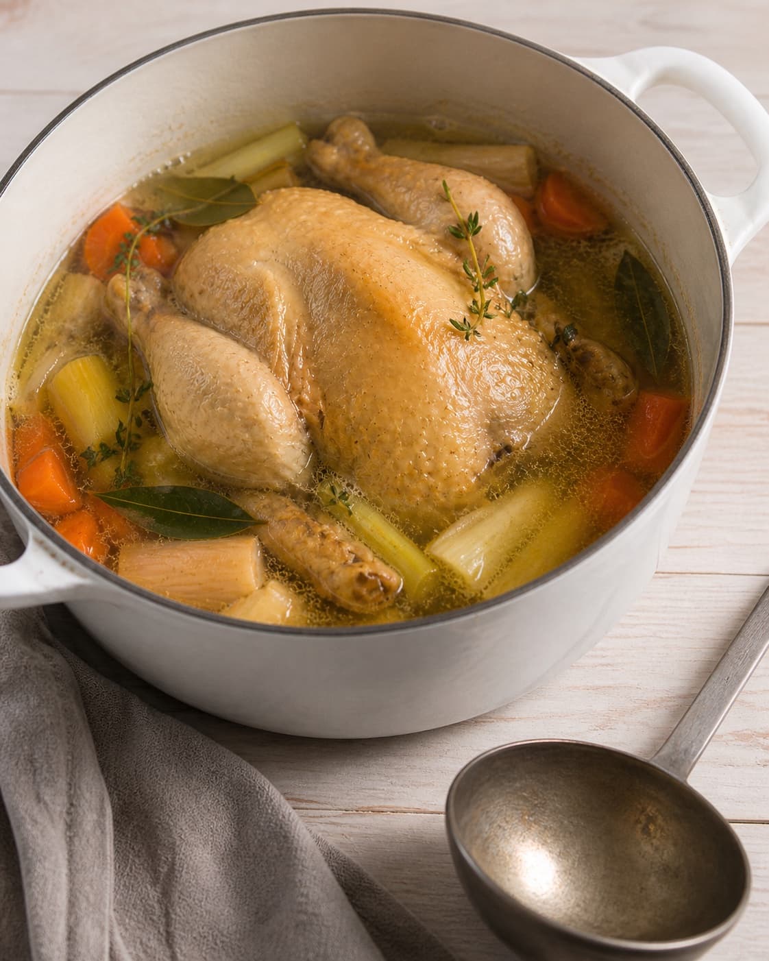 One single photorealistic instructional frame of the stew gently braising with tender meat and vegetables for Grydestegt kylling og hjemmelavet kyllingefond - bouillion, featuring hel kylling, gulerødder, porrer, with only the named equipment and no unrelated food, text, logos or packaging under tilberedningen af grydestegt kylling og hjemmelavet kyllingefond - bouillion