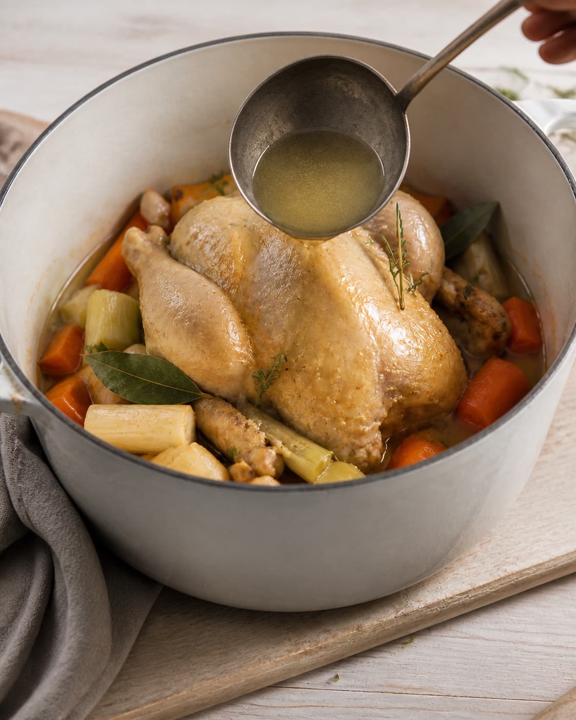 One single photorealistic instructional frame of the finished glossy stew ready in one serving pot for Grydestegt kylling og hjemmelavet kyllingefond - bouillion, featuring hel kylling, gulerødder, porrer, with only the named equipment and no unrelated food, text, logos or packaging under tilberedningen af grydestegt kylling og hjemmelavet kyllingefond - bouillion