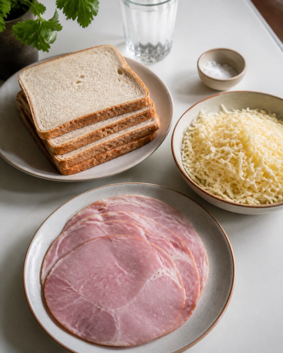 One single photorealistic instructional frame of prepared filling ingredients arranged separately for Croque Monsieur og Croque Madame, featuring toastbrød, skinke, gruyère, with only the named equipment and no unrelated food, text, logos or packaging under tilberedningen af croque monsieur og croque madame