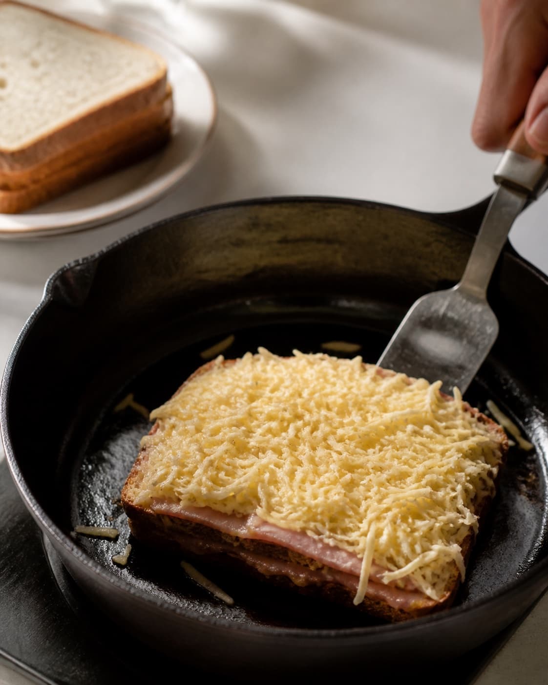 One single photorealistic instructional frame of the savoury filling browning in one skillet for Croque Monsieur og Croque Madame, featuring toastbrød, skinke, gruyère, with only the named equipment and no unrelated food, text, logos or packaging under tilberedningen af croque monsieur og croque madame