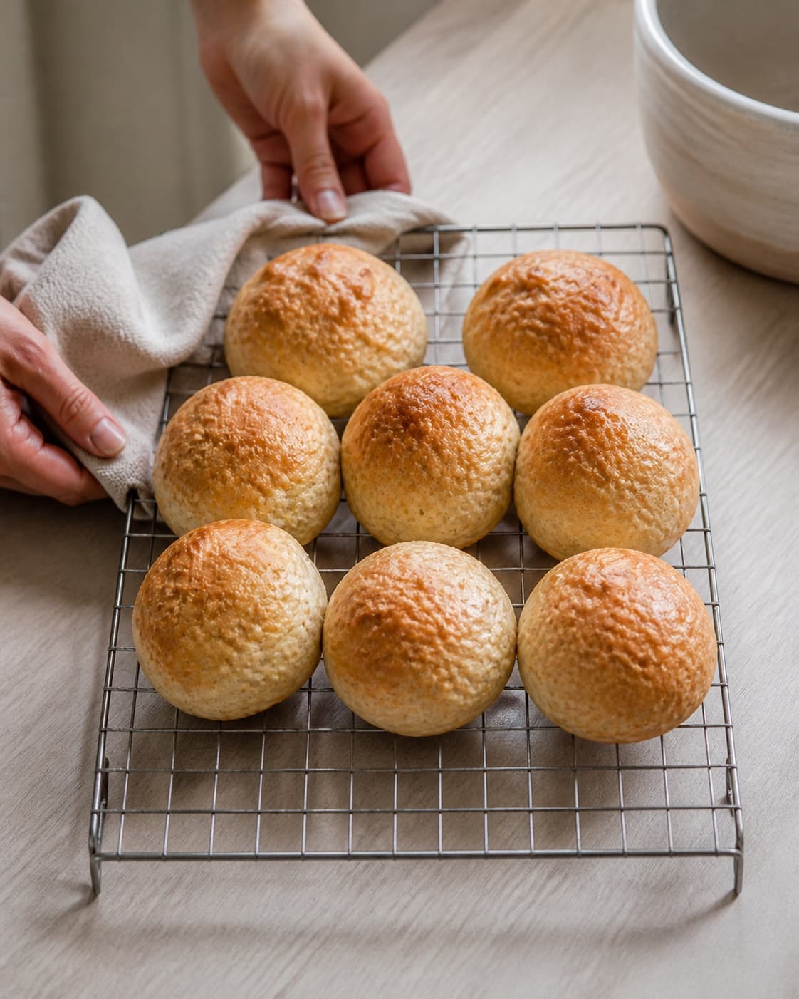 One single photorealistic instructional frame of freshly baked golden bread cooling on one rack for Boller med ris, featuring hvedemel, kogte ris, gær, with only the named equipment and no unrelated food, text, logos or packaging under tilberedningen af boller med ris