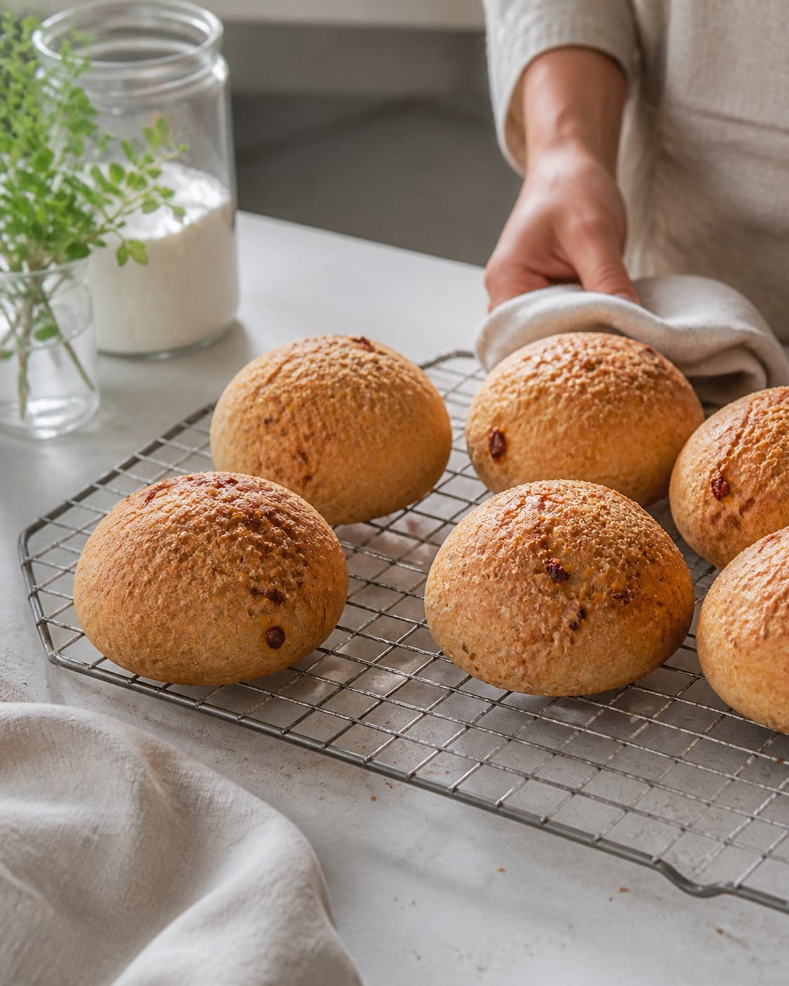 One single photorealistic instructional frame of freshly baked golden bread cooling on one rack for Madbrød med soltørrede tomater, chili og parmesan, featuring hvedemel, gær, soltørrede tomater, with only the named equipment and no unrelated food, text, logos or packaging under tilberedningen af madbrød med soltørrede tomater, chili og parmesan