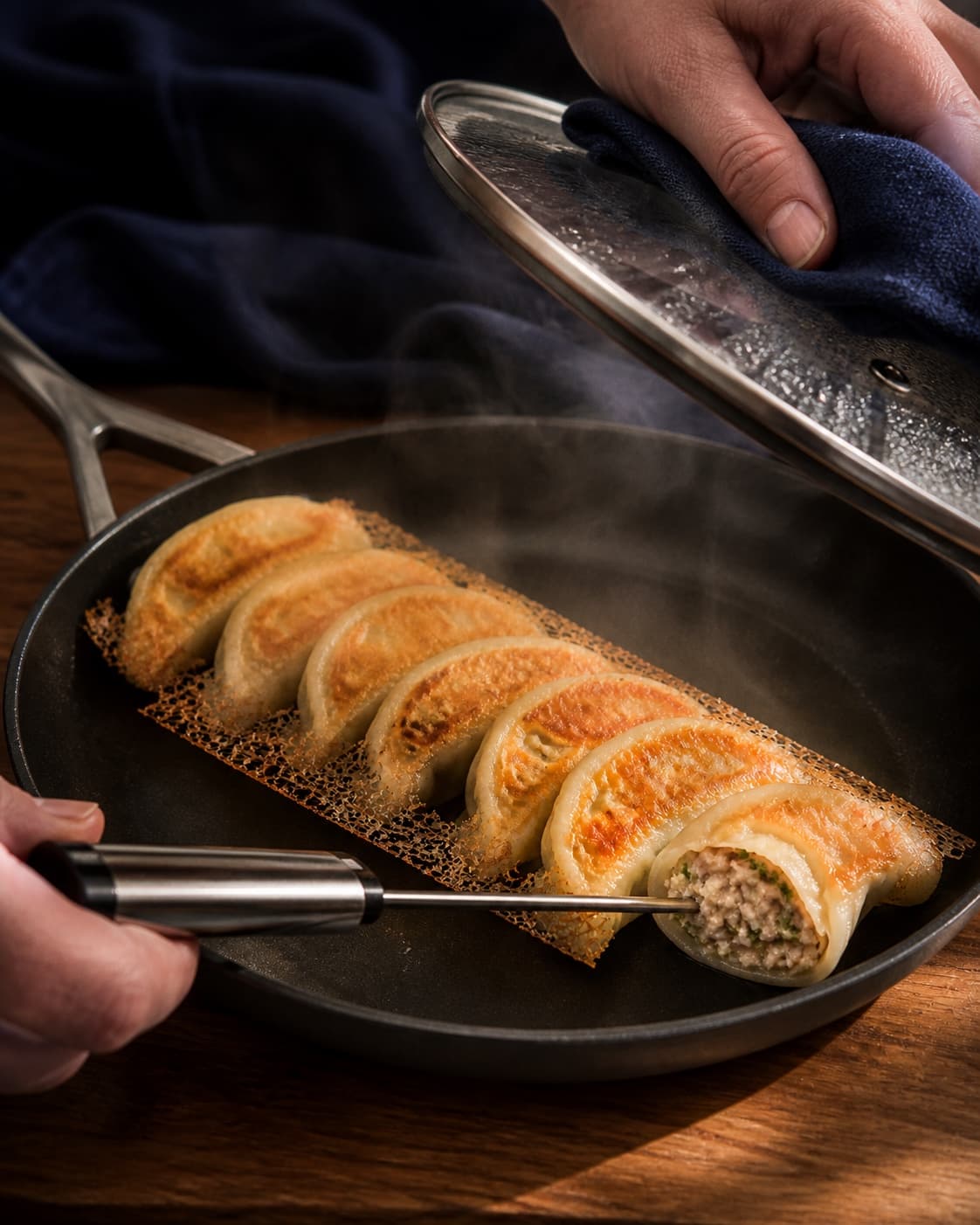 To hænder løfter låget væk fra dampen og fører termometerproben tydeligt ind i det uigennemsigtige fyld i én kontroldumpling