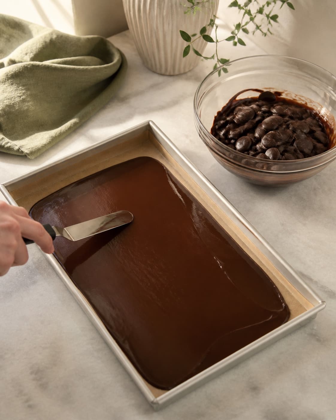 Blank tempereret mørk chokolade stryges til et ensartet tyndt bundlag i en tør bagepapirsforet rektangulær form