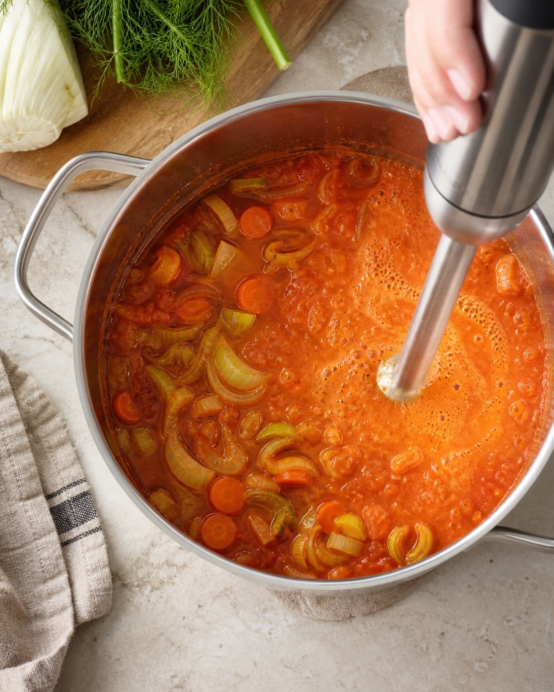 Kun den ene side af den murstensrøde tomatbouillon blendes, mens møre stykker af fennikel, porre og gulerod forbliver tydelige i resten
