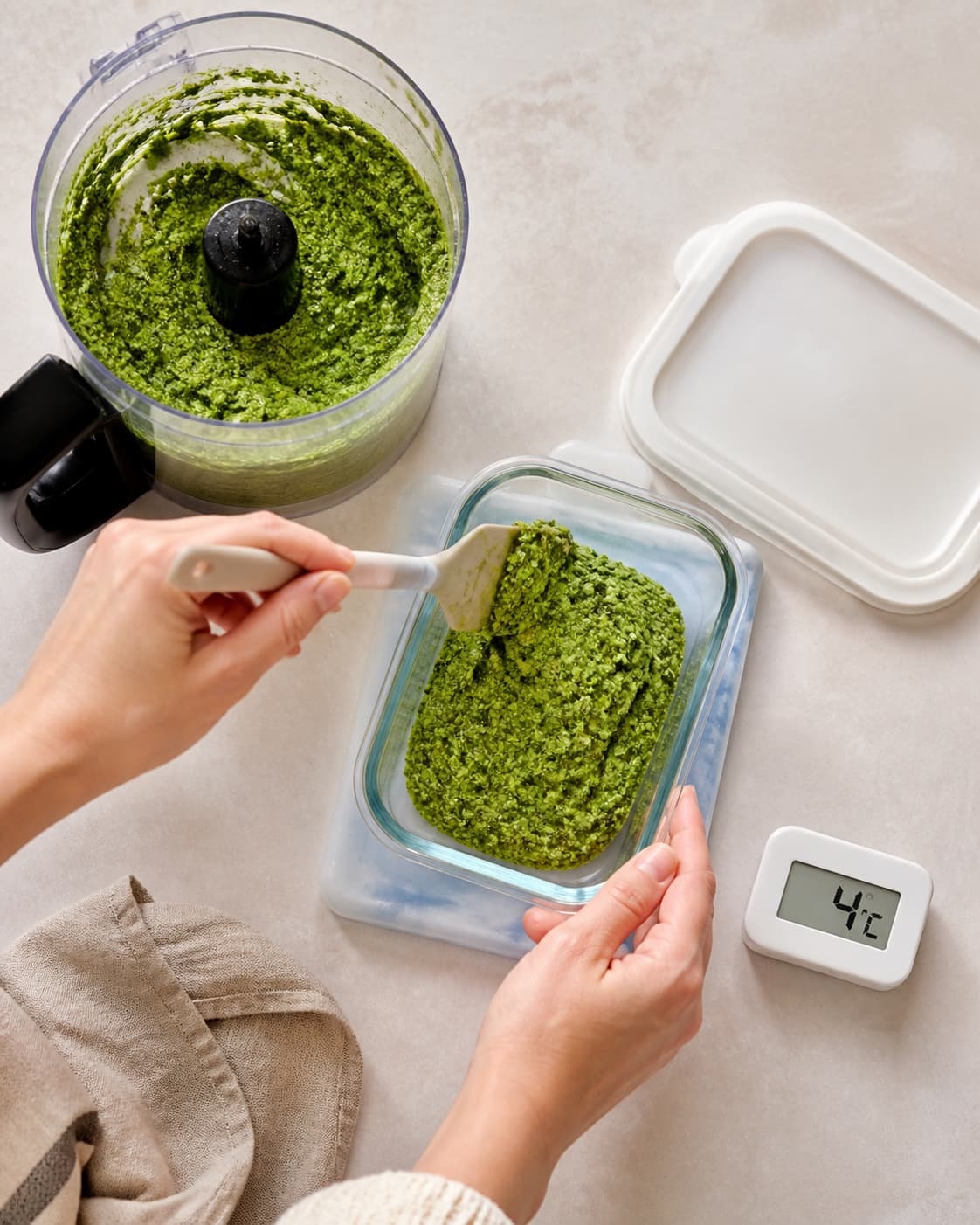 Tæt klart grøn pesto med fine græskarkernepletter flyttes med rent redskab til en ren beholder på køleelement ved 4 °C uden oliesø