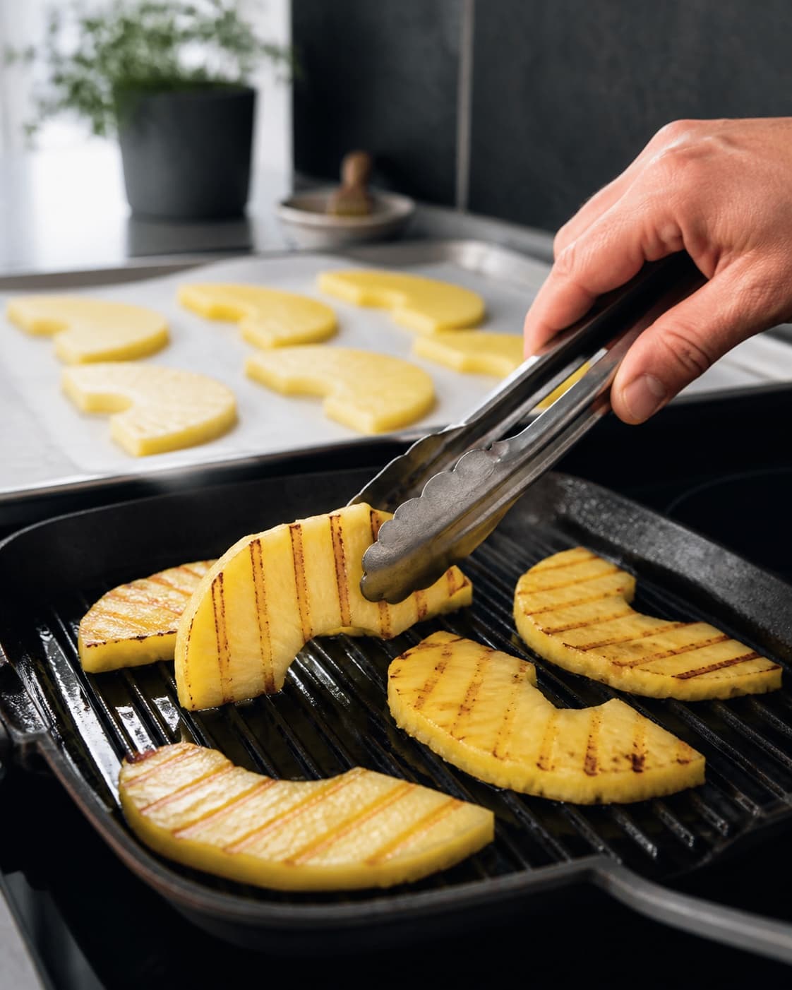 Tynde saftige ananas-halvmåner vendes på en meget varm grillpande med klare gyldne striber og fleksibel gul frugt uden sorte kanter