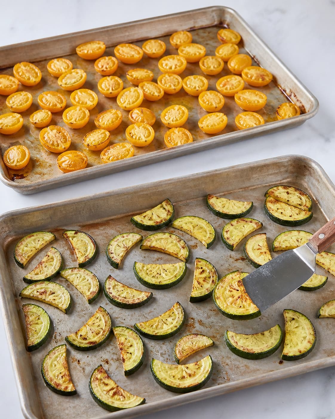 Saftige let sammenfaldne gule tomater og gyldne courgette-halvmåner ristes hver for sig i ét lag på to tydeligt adskilte plader