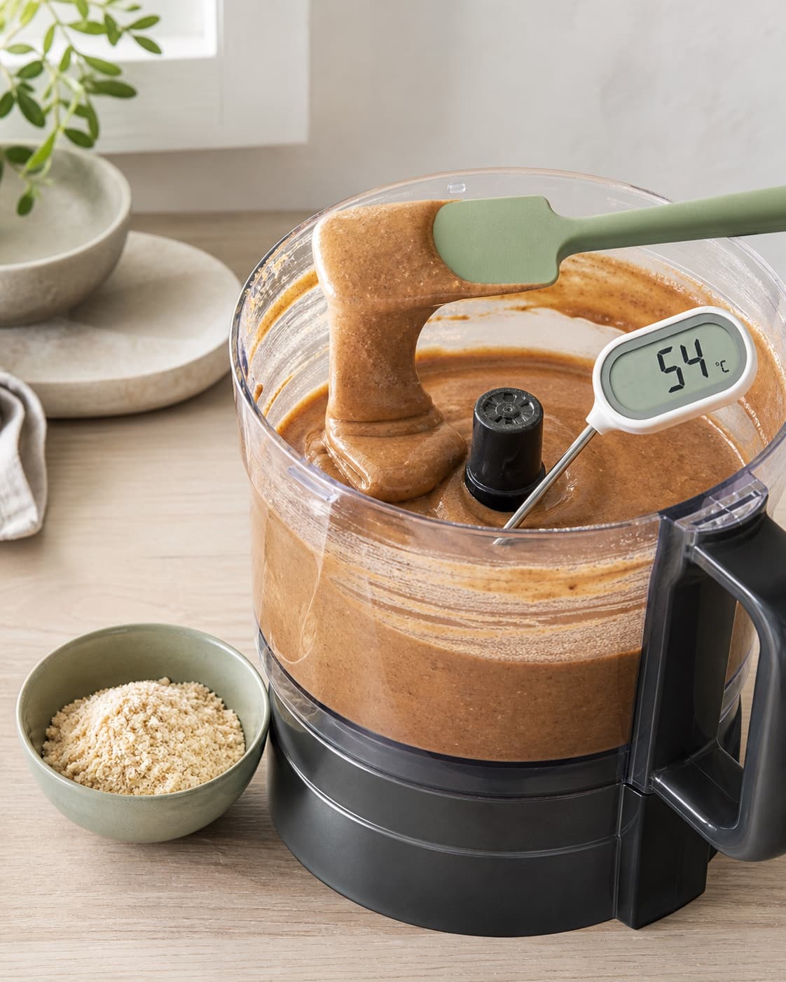 Silkeblødt blankt mandelsmør falder i en tyk ubrudt bølge i den standsede foodprocessor, mens massen måles til præcis 54 °C