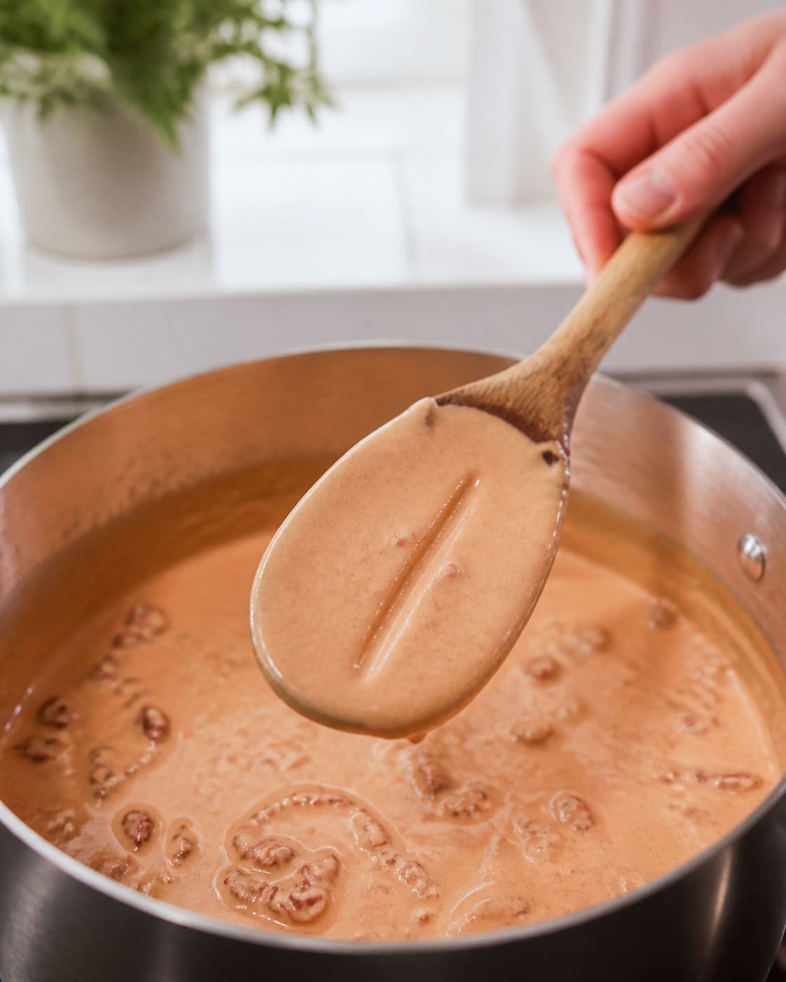 Blank lyserød soltomat-flødesauce dækker bagsiden af en træske med en ren streg uden rå tomatpuré, frit fedt eller hård kogning